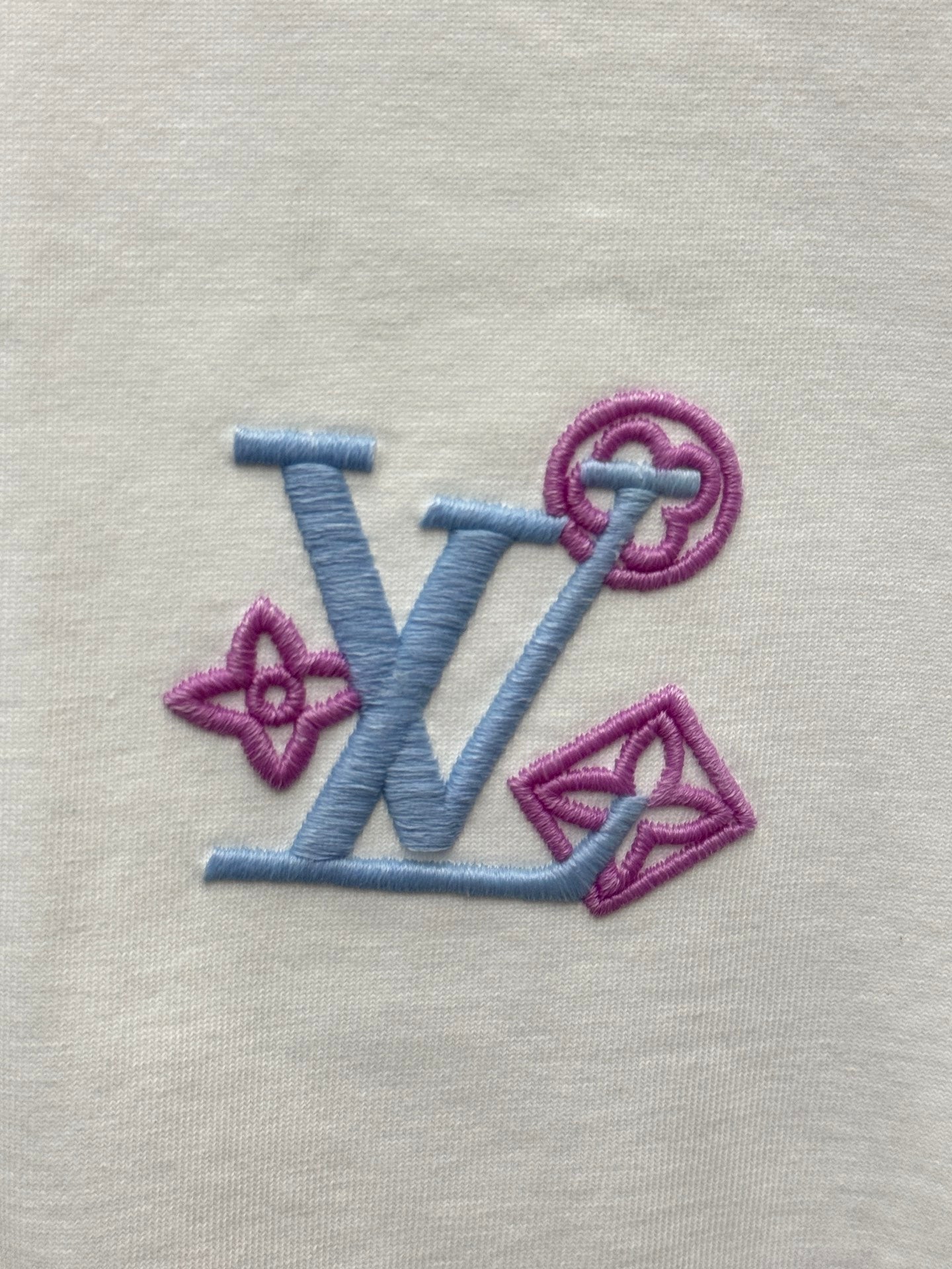 Embroidered Louis Vuitton-style logo on white fabric, blue and purple