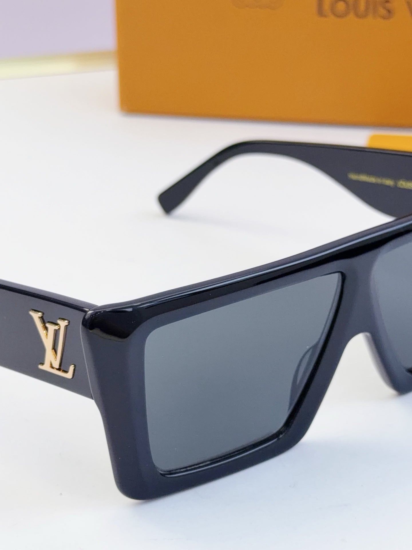 Louis Vuitton black square sunglasses with dark lenses and gold LV logo on side.