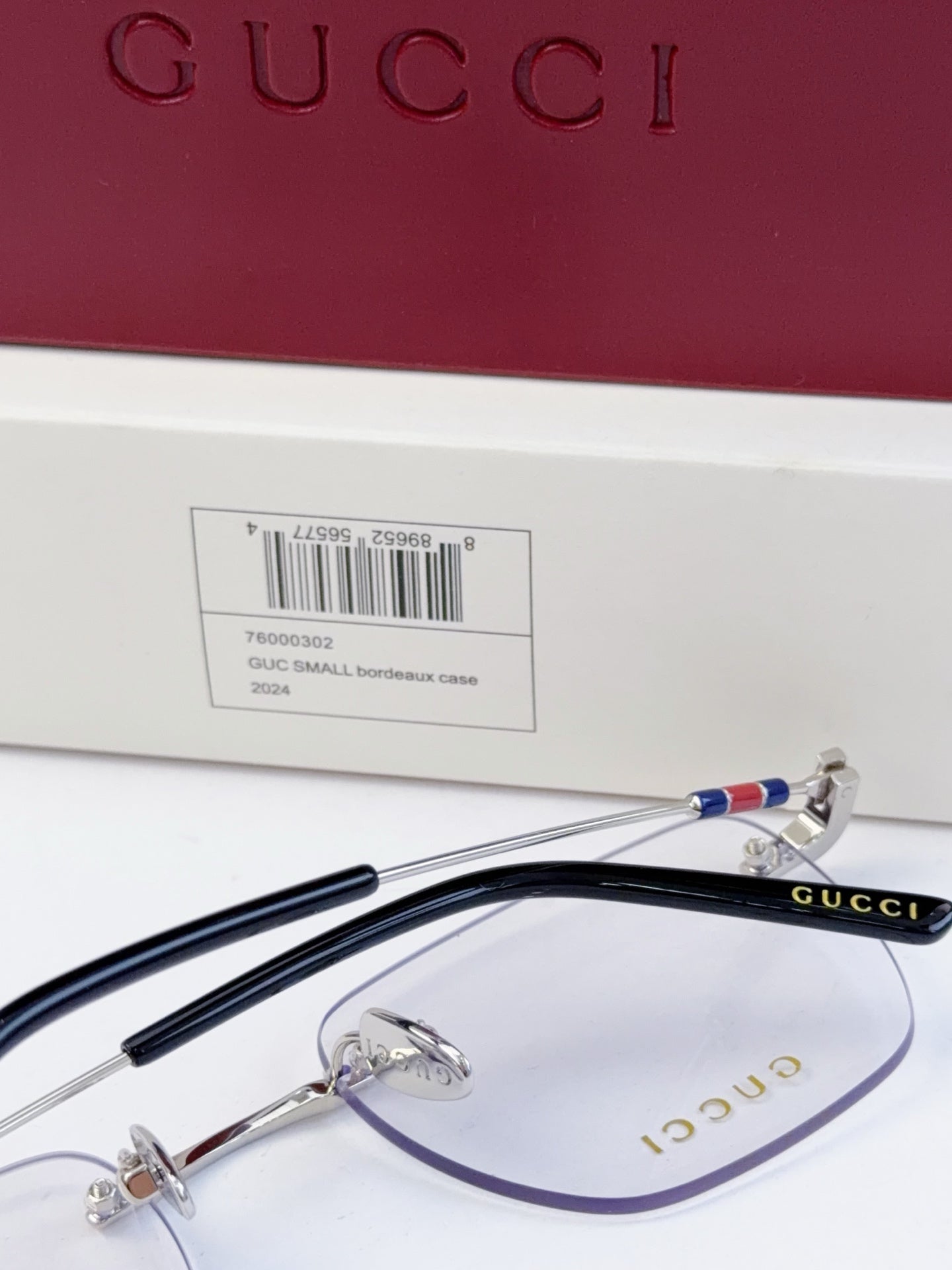 Gucci eyeglasses close-up, clear lenses with metal frame, temples with multicolor stripe detail