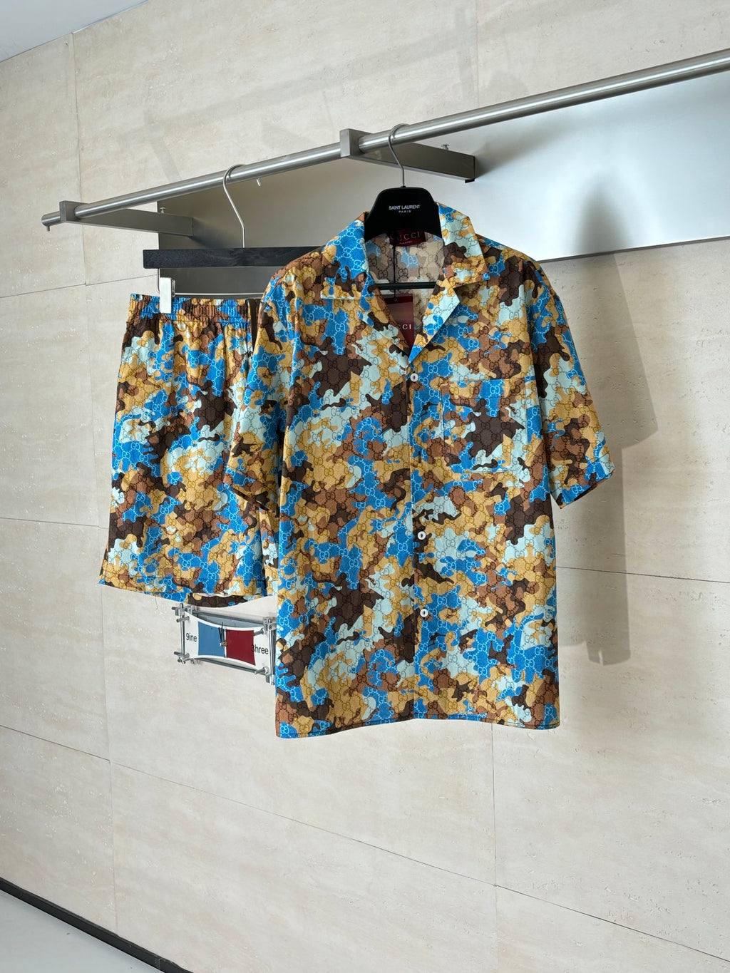 Short-sleeve button-up shirt on hanger, full view of blue and tan abstract pattern