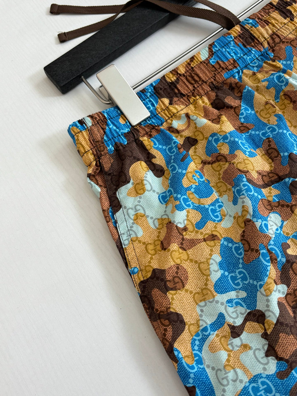 Gucci patterned shorts fabric swatch, blue and brown all-over repeat design.