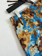 Gucci patterned shorts fabric swatch, blue and brown all-over repeat design.