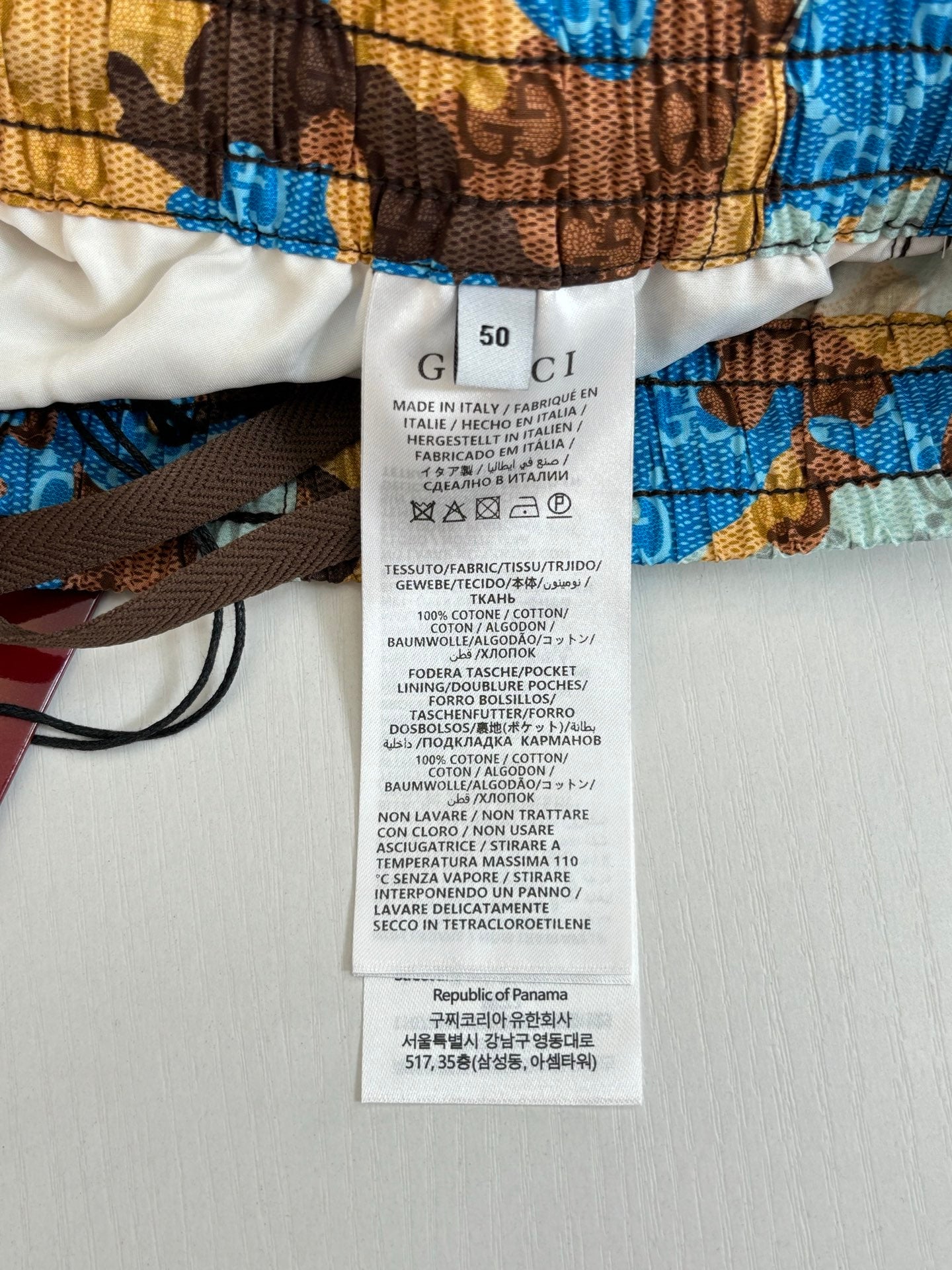 Gucci shorts care label tags on waistband, blue and brown all-over print.