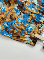 Gucci shorts hem detail, blue and brown all-over print with visible stitching.