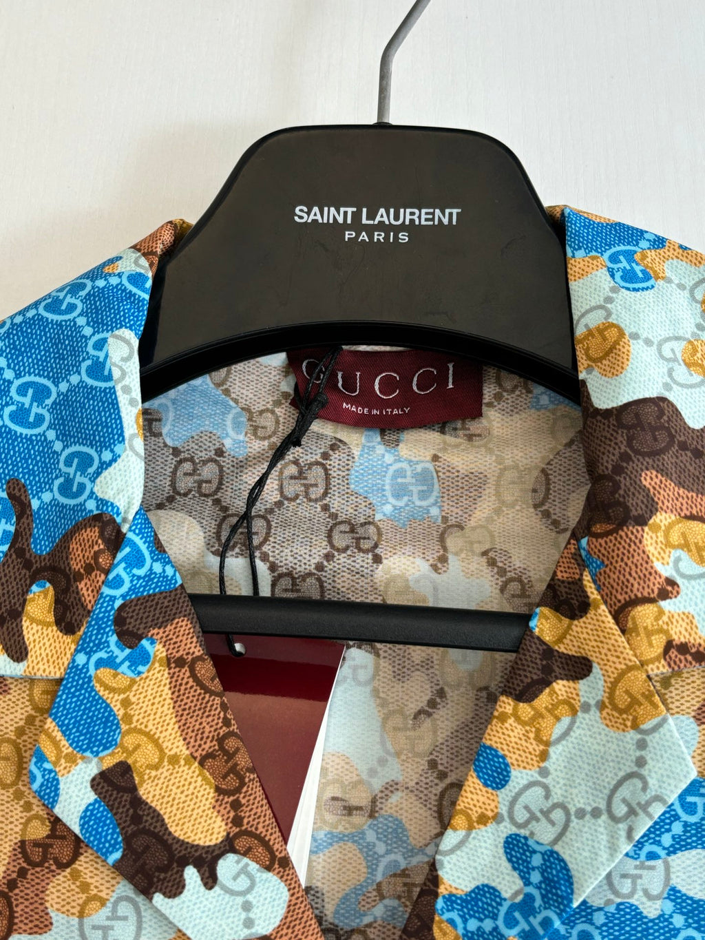 Short-sleeve shirt close-up on hanger, blue and brown abstract print, fabric tag