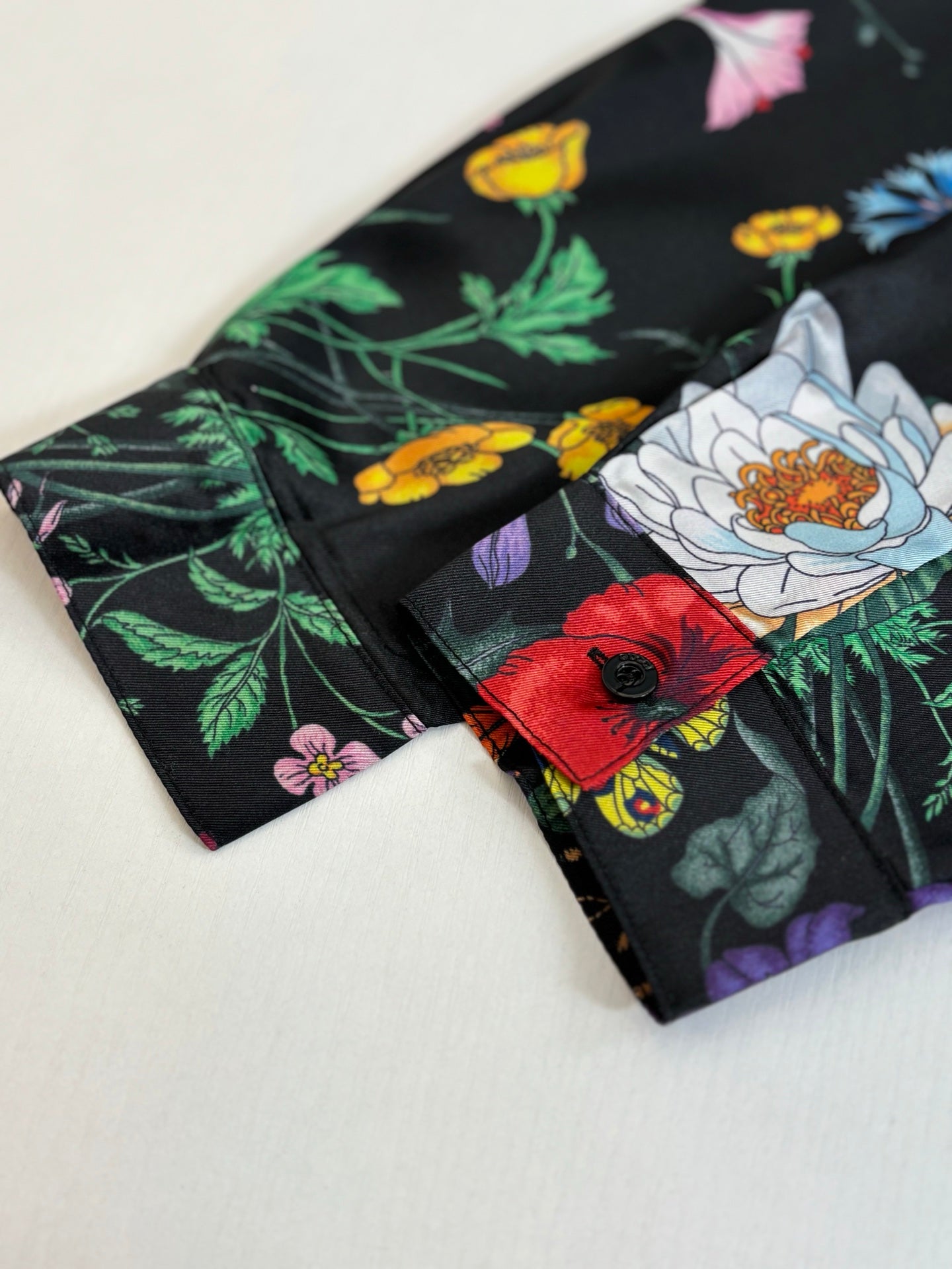 Folded black shirt showing multicolor flowers and insects print