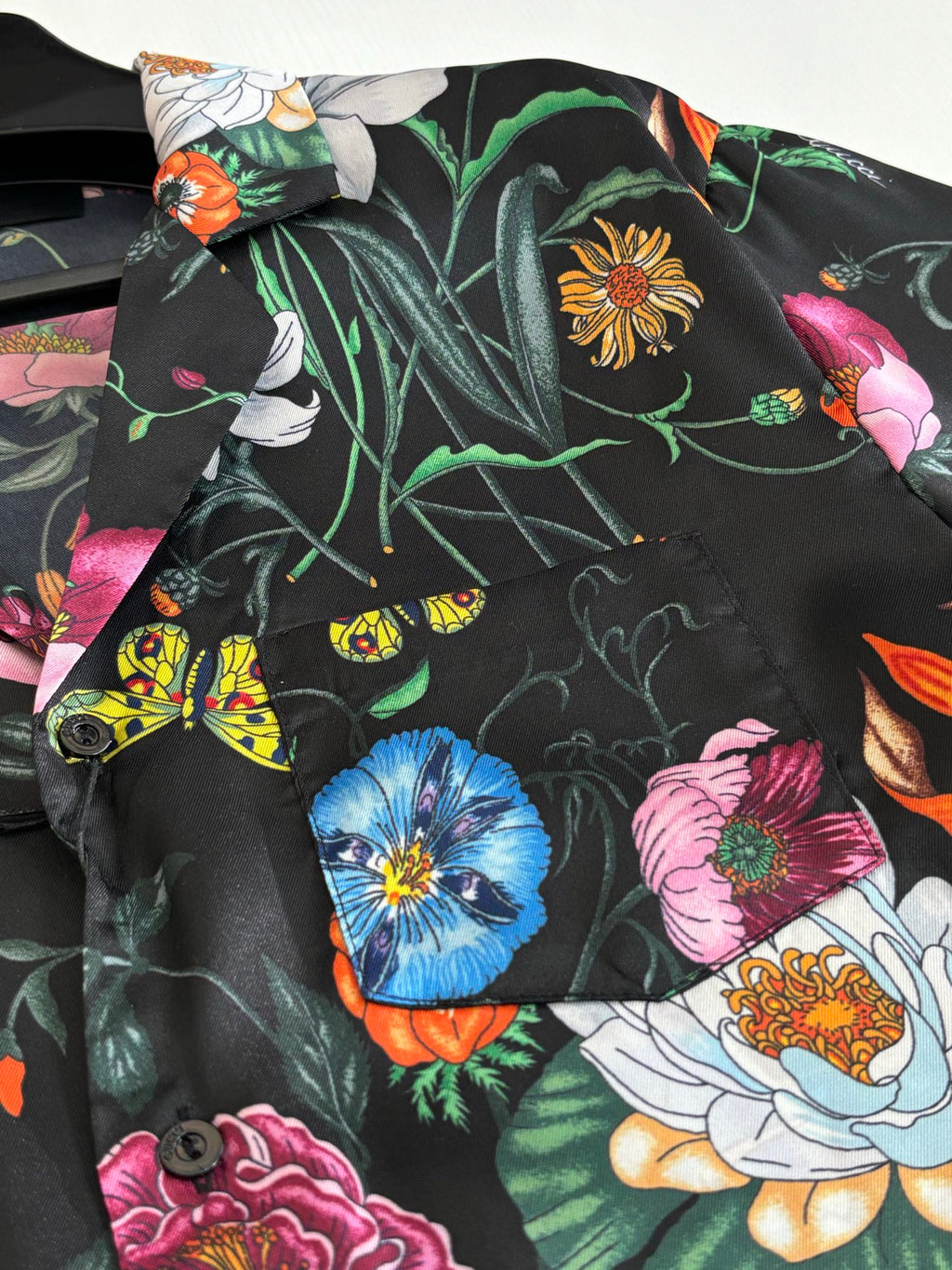 Black shirt fabric detail with colorful flowers and insects pattern