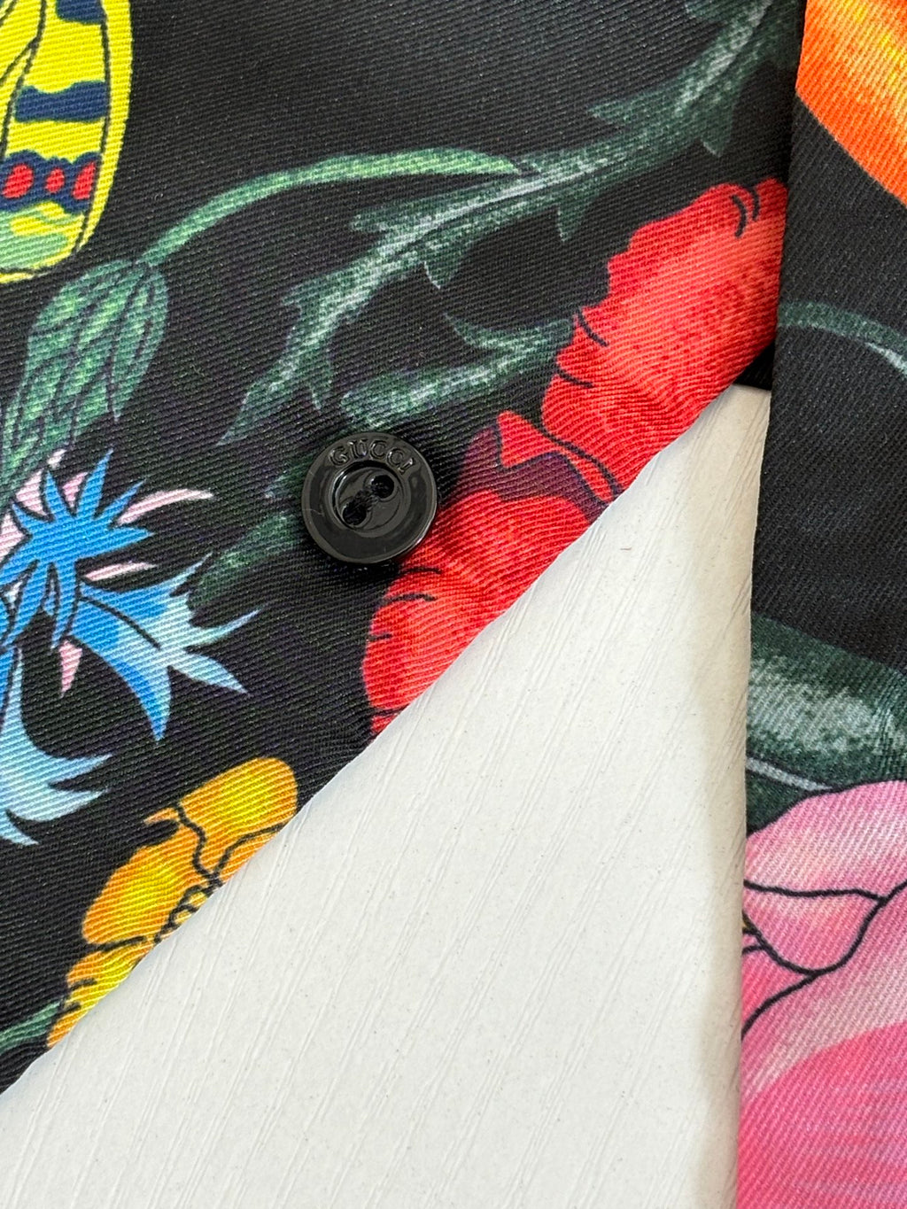 Buttoned cuff detail on dark shirt with colorful botanical print