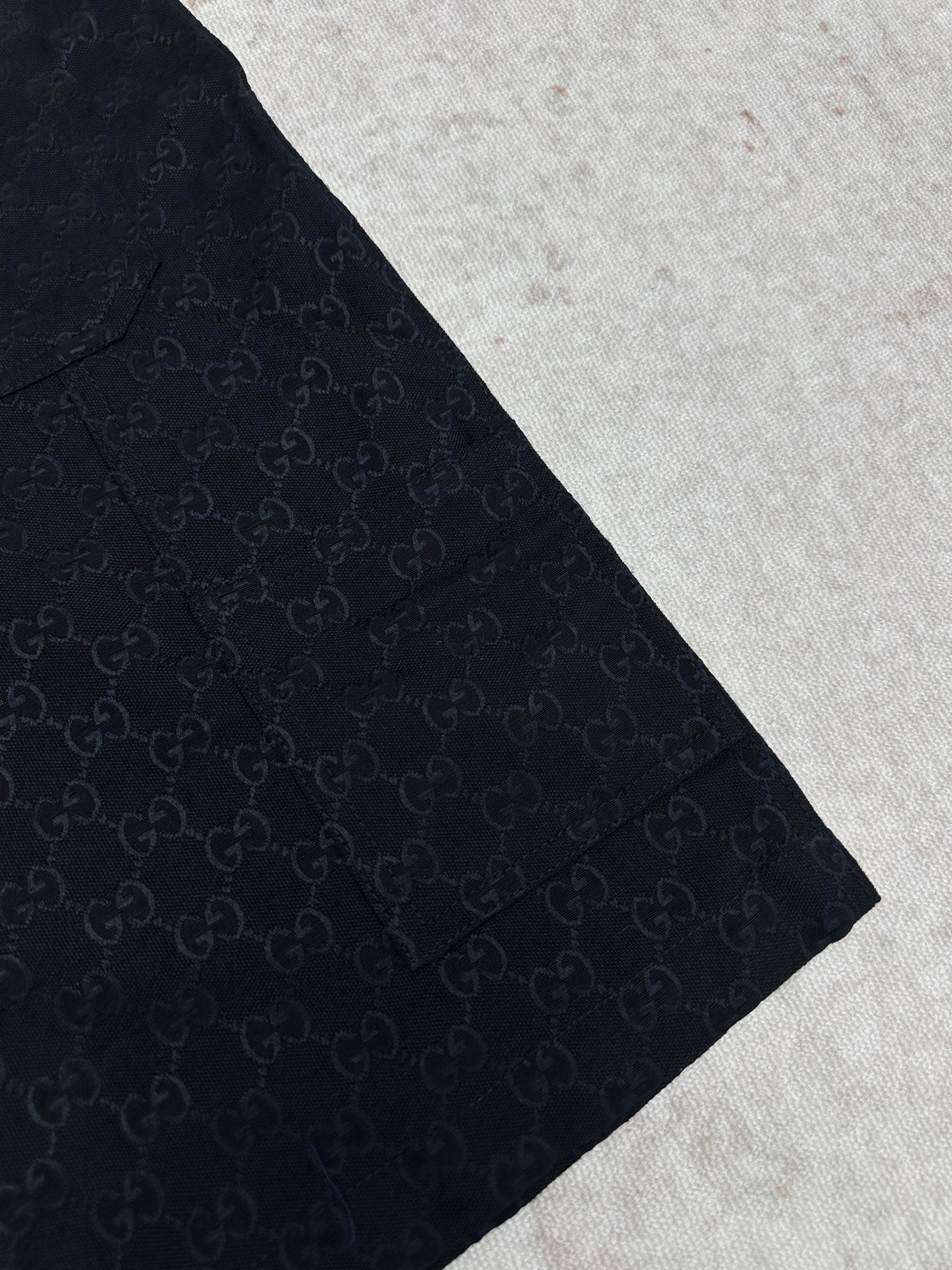 Gucci dark navy shorts with GG-style monogram pattern, side view and tapered hem