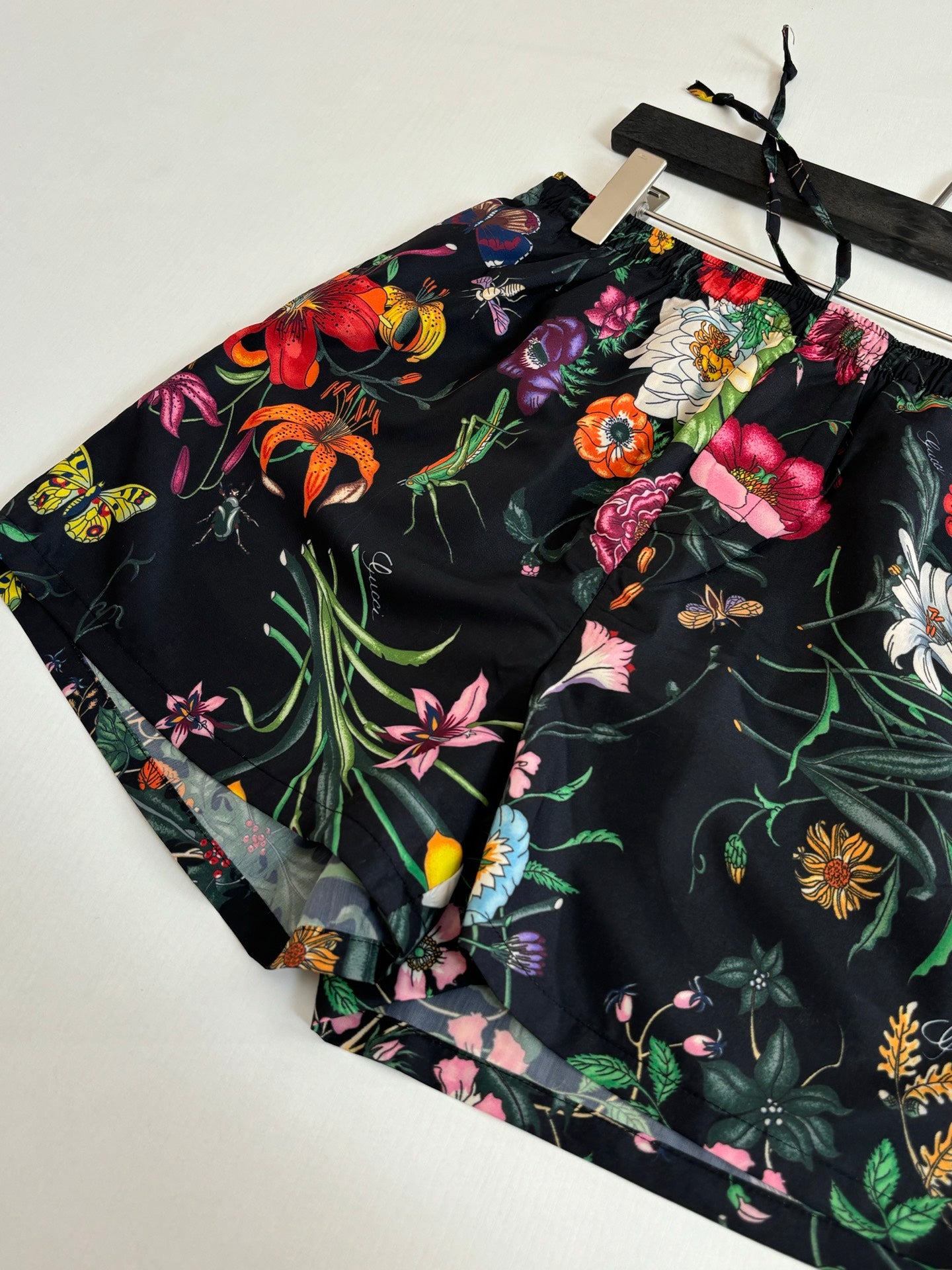 Gucci floral shorts fabric close-up showing black base and colorful blooms
