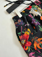 Gucci floral shorts fabric close-up on flat surface, black with bright flowers