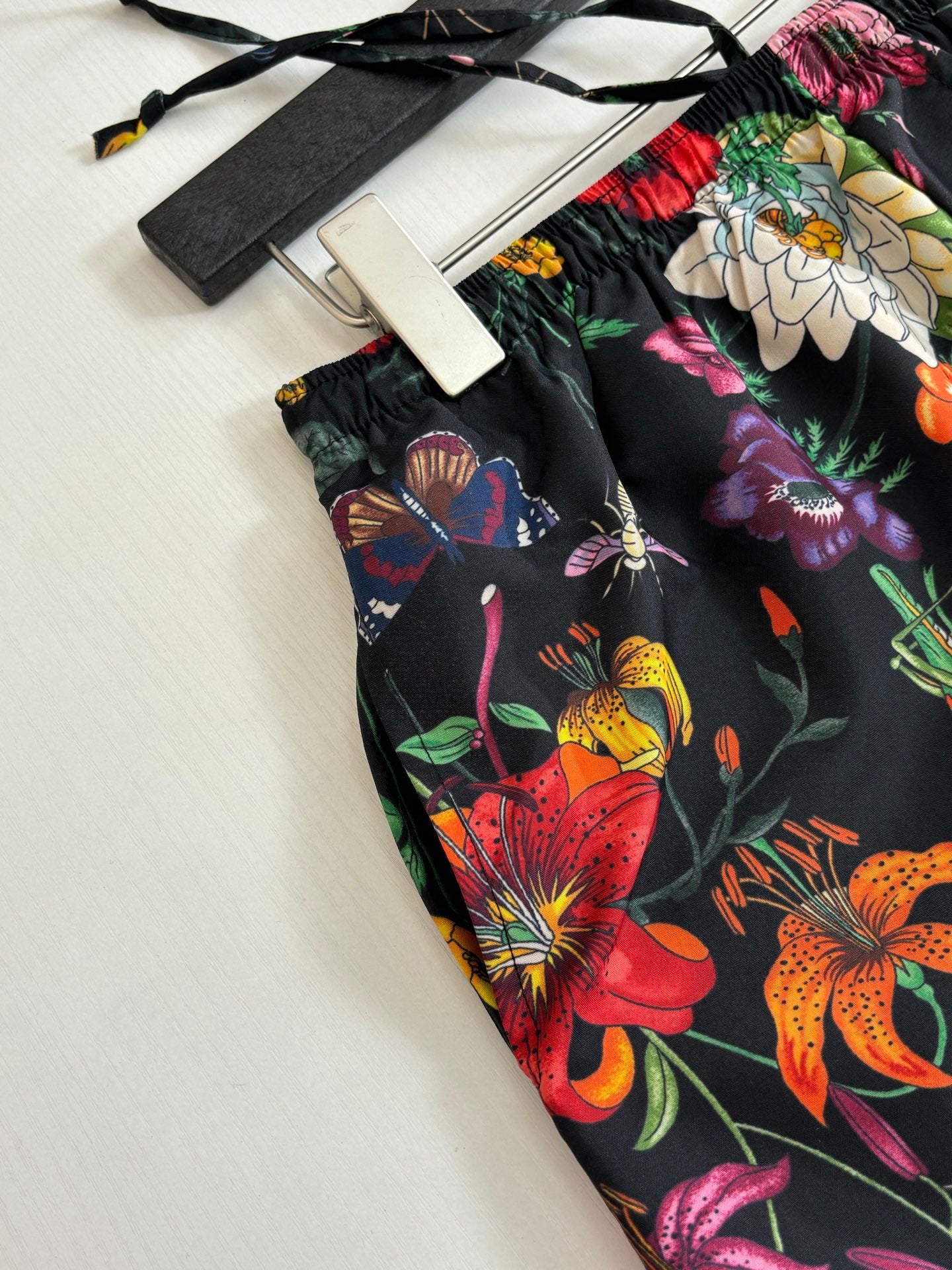 Gucci floral shorts fabric close-up on flat surface, black with bright flowers