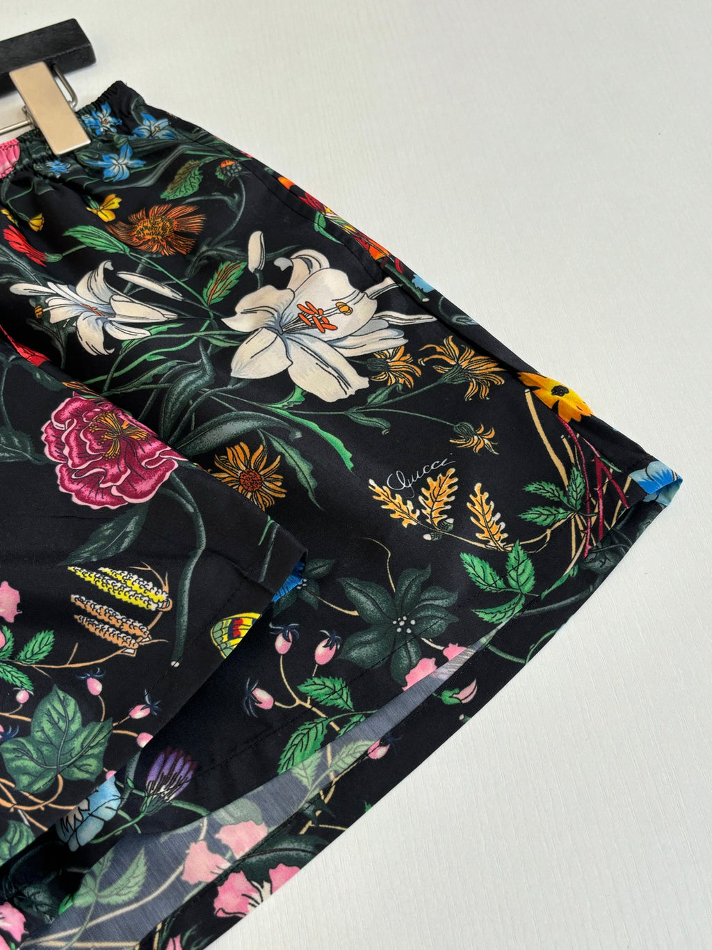 Gucci floral print shorts close-up with large flowers and foliage on black