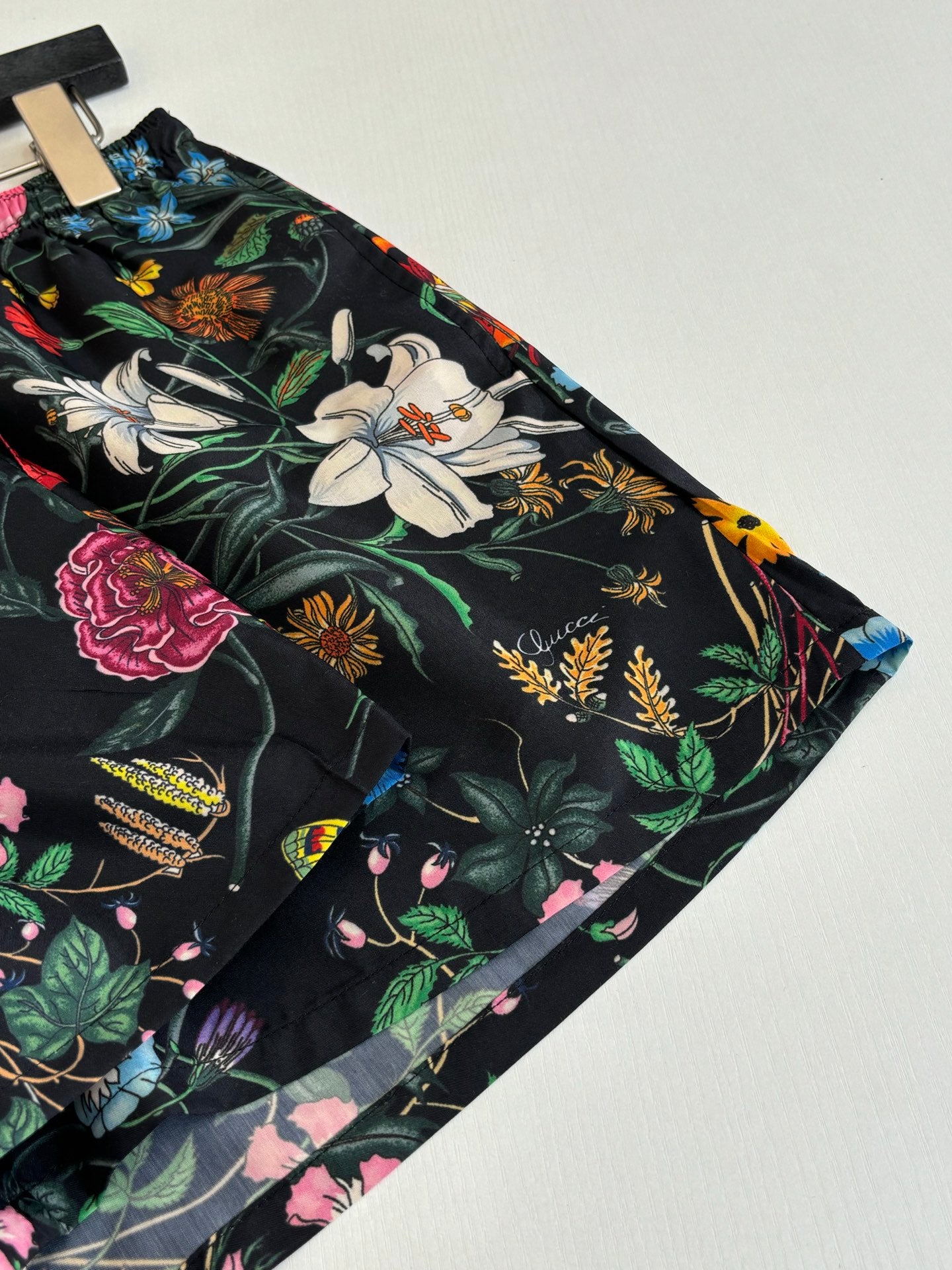 Gucci floral print shorts close-up with large flowers and foliage on black