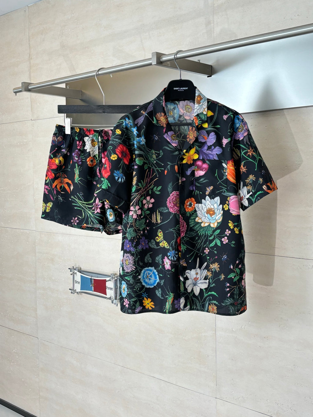 Black Gucci short-sleeve shirt on hanger with colorful flower and leaf print