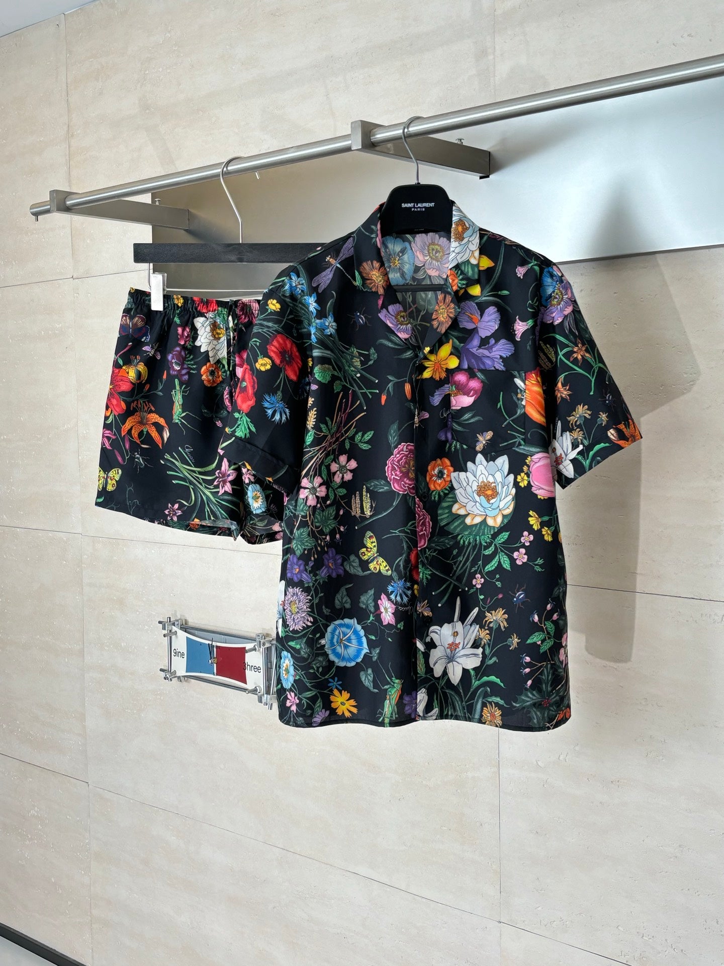 Black Gucci short-sleeve shirt on hanger with colorful flower and leaf print