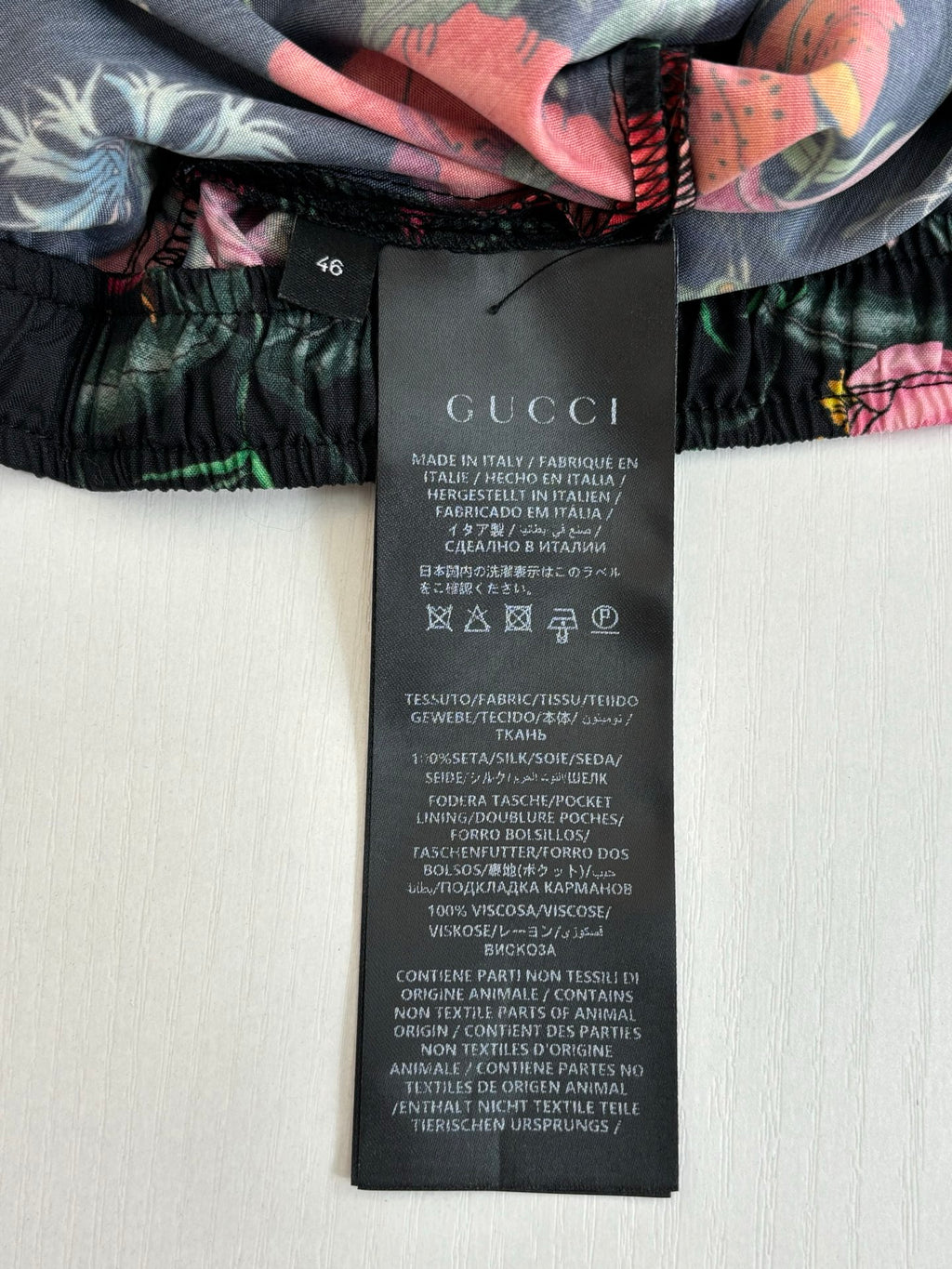 Gucci clothing tag on floral shorts; black care label attached