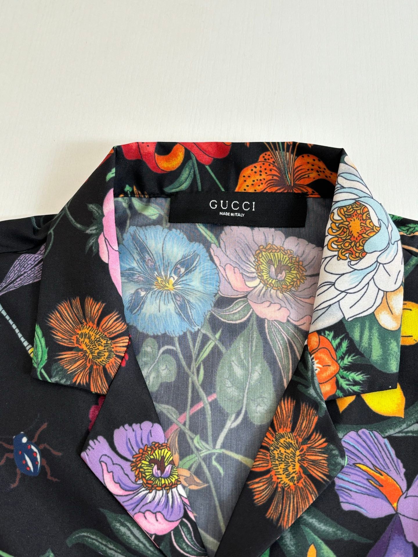 Gucci short-sleeve shirt fabric close-up, multicolor floral print on dark base