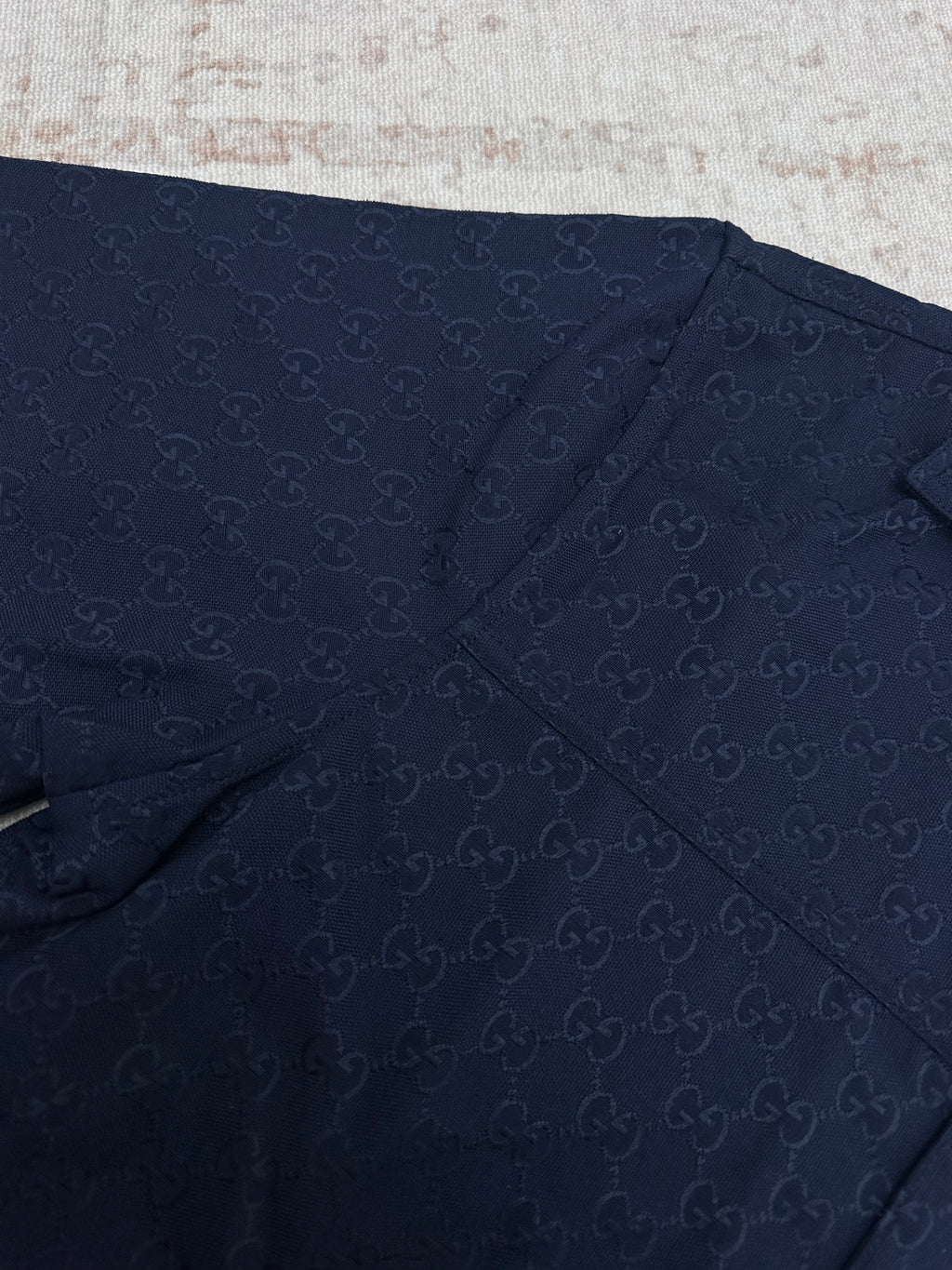 Dark navy short-sleeve shirt fabric with stitched seams and subtle GG pattern