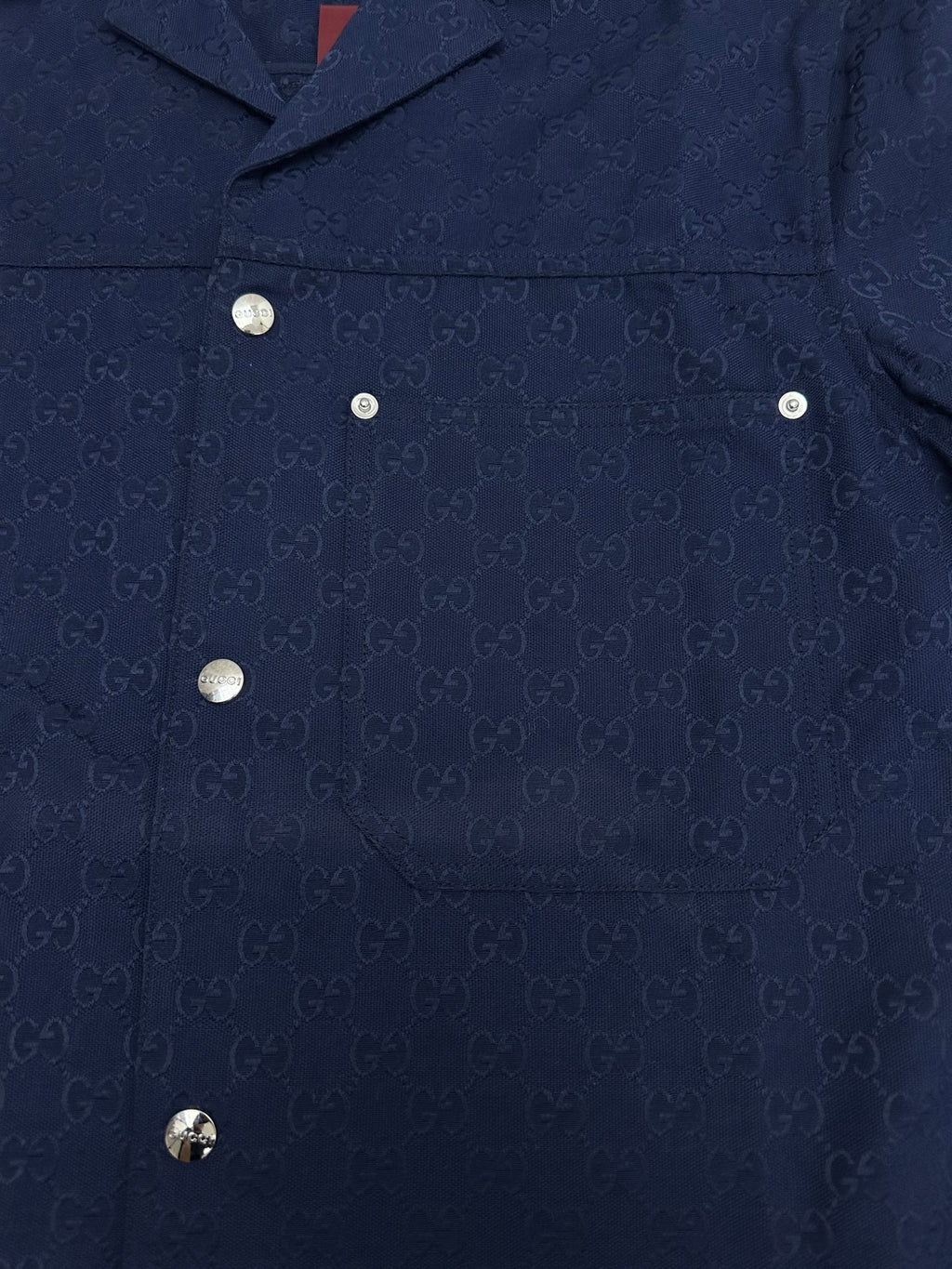 Dark navy short-sleeve button-up shirt front with metal buttons and patch pocket details