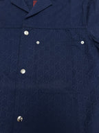 Dark navy short-sleeve button-up shirt front with metal buttons and patch pocket details