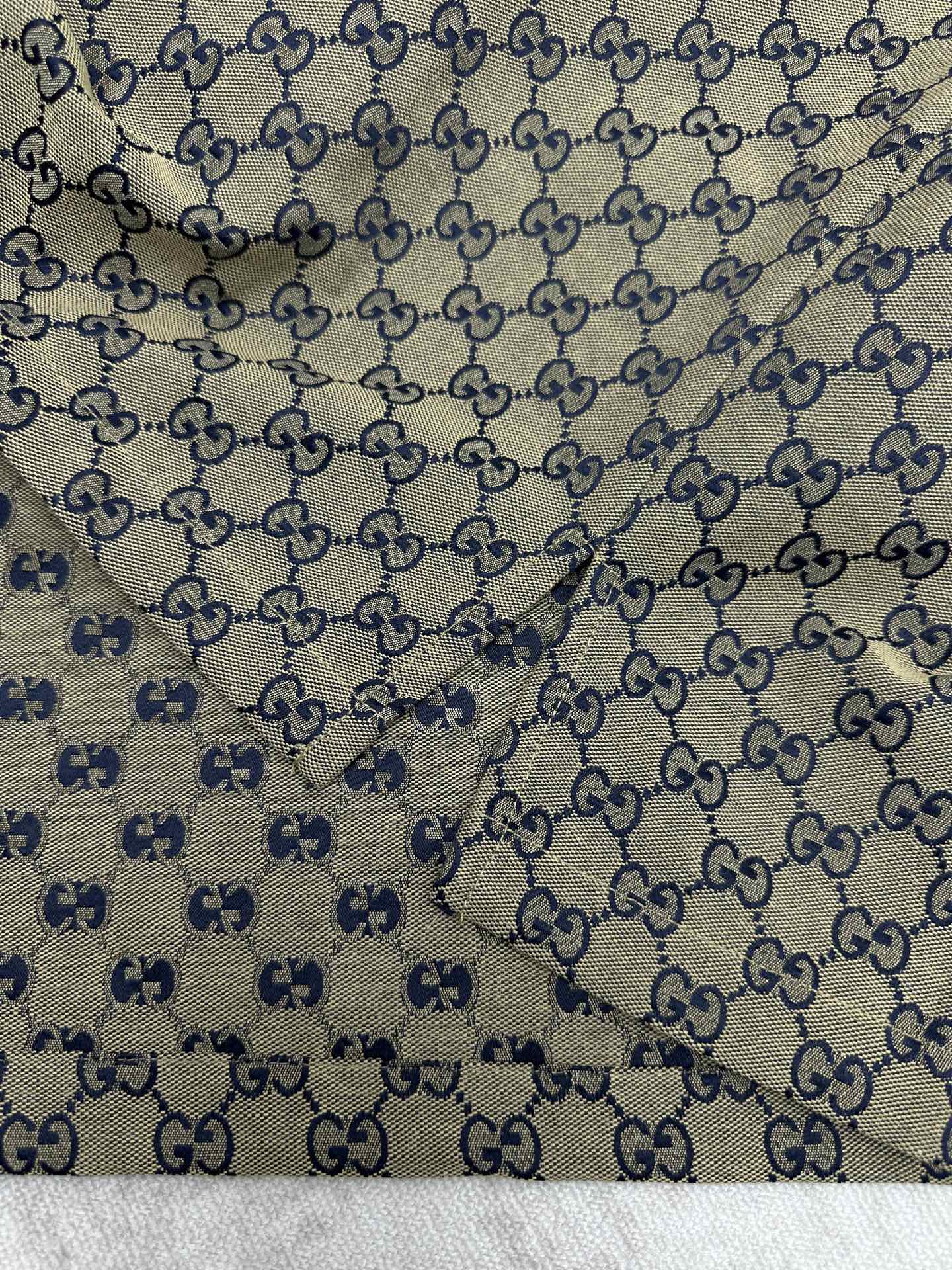 Gucci short-sleeve shirt fabric close-up with GG logo pattern and blue motif