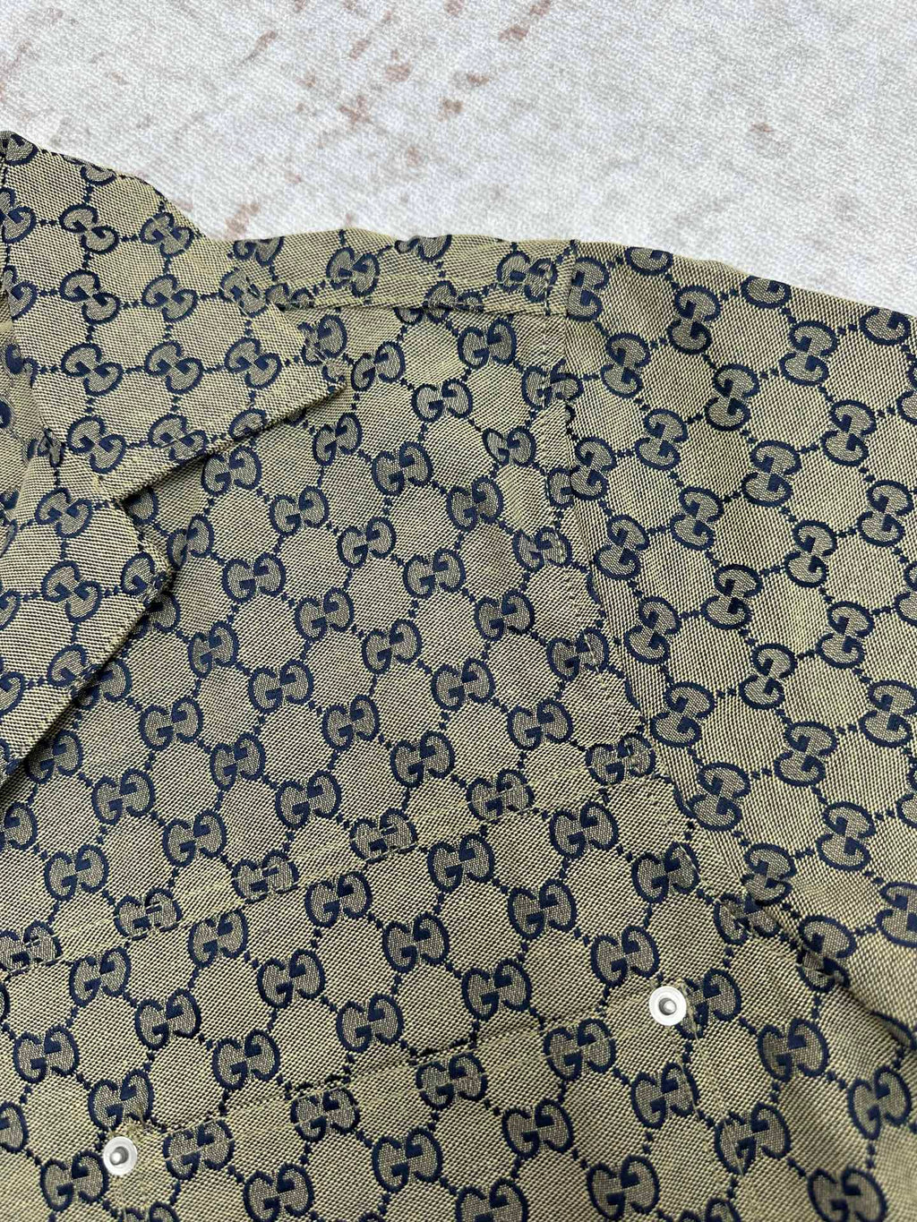 Gucci short-sleeve shirt fabric close-up with GG pattern and blue trim