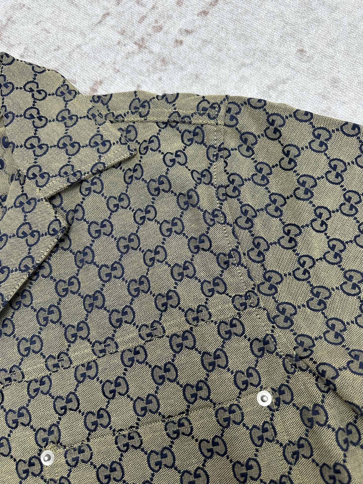 Gucci short-sleeve shirt fabric close-up with GG pattern and blue trim
