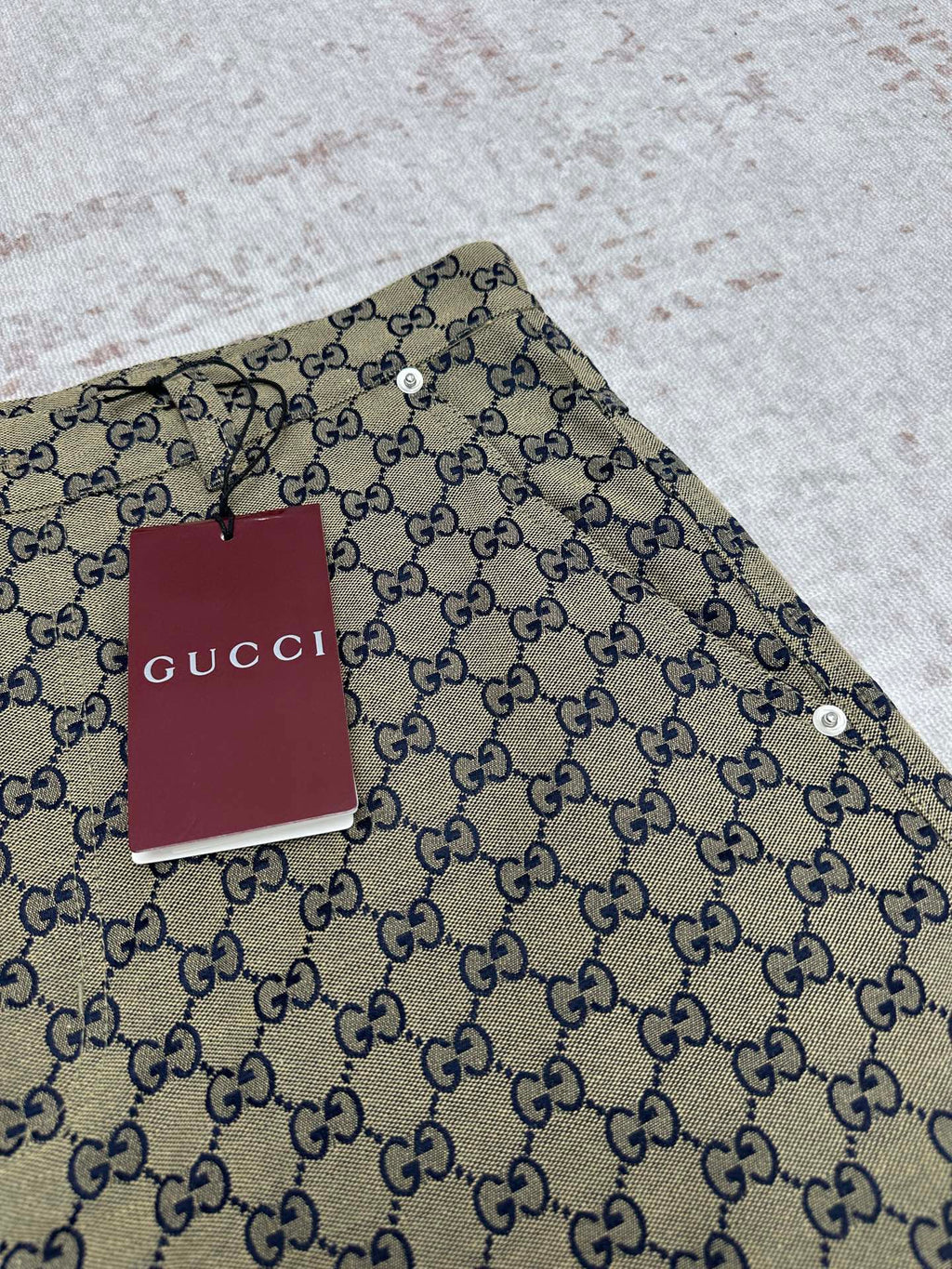 Gucci shorts close-up of GG monogram fabric with metal button and waistband