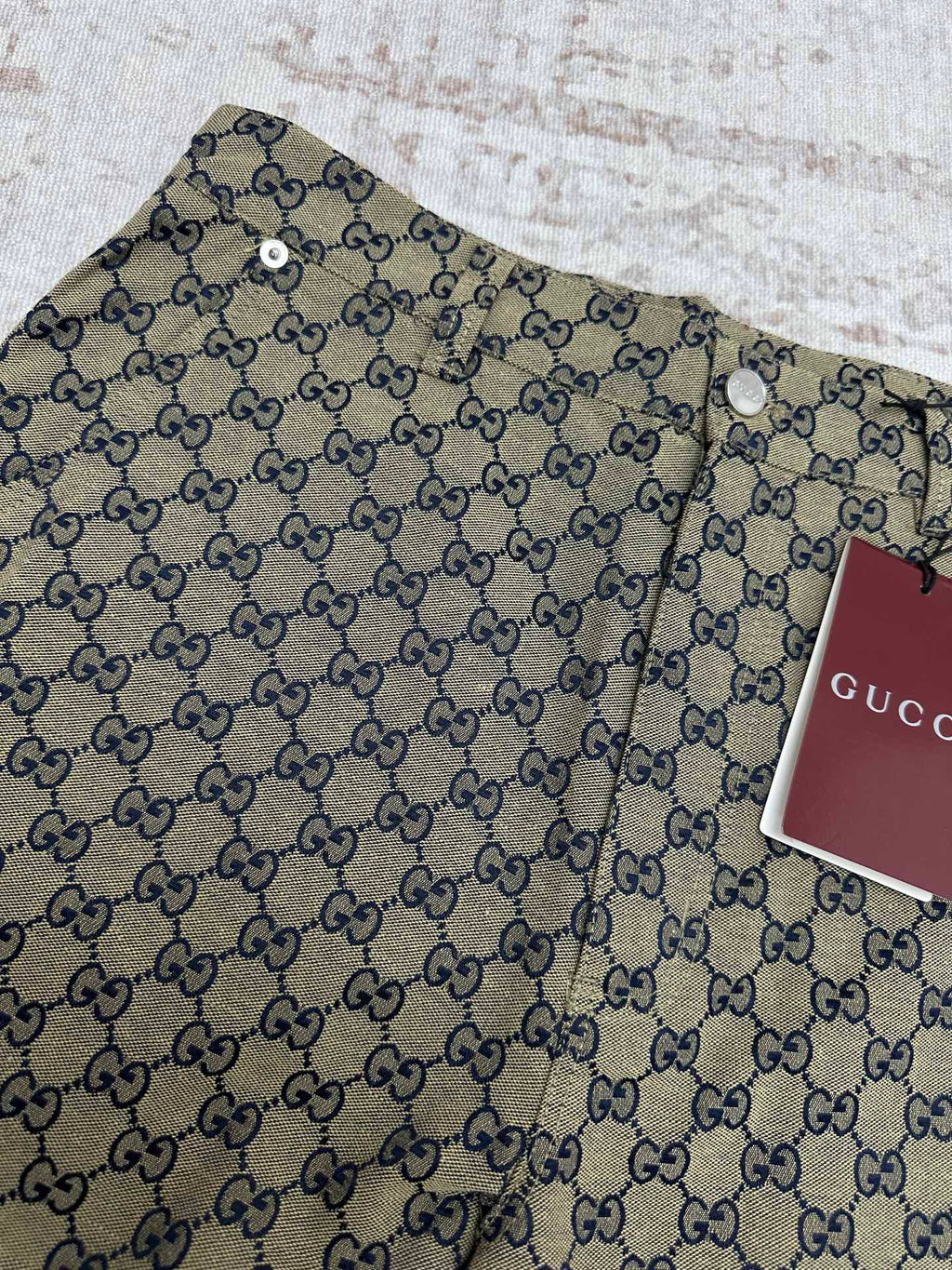 Gucci shorts close-up showing GG monogram print, button detail and waistband