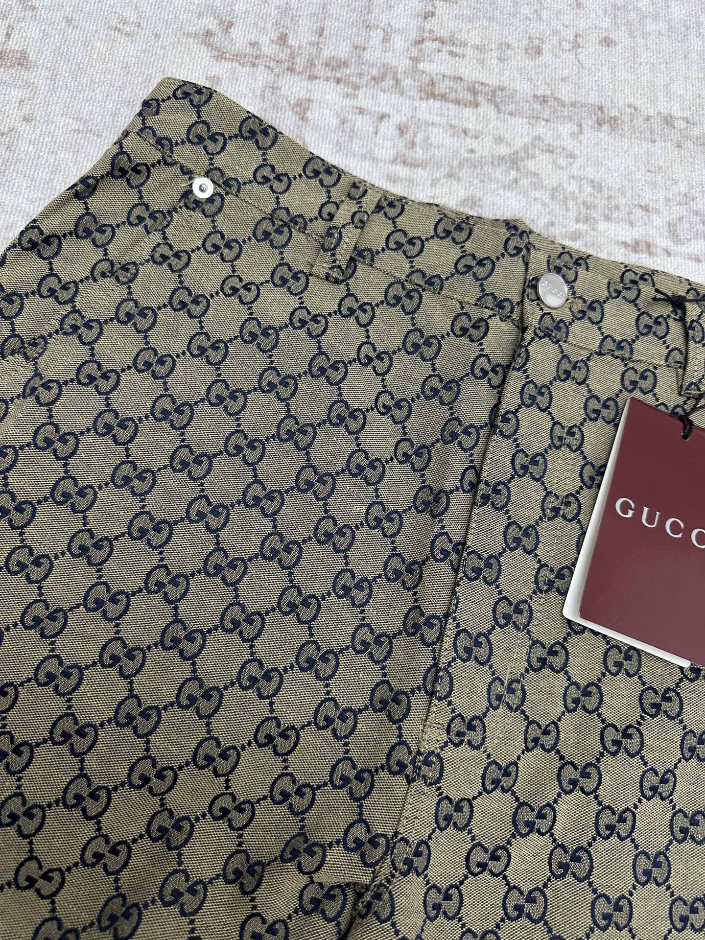 Gucci shorts close-up showing GG monogram print, button detail and waistband