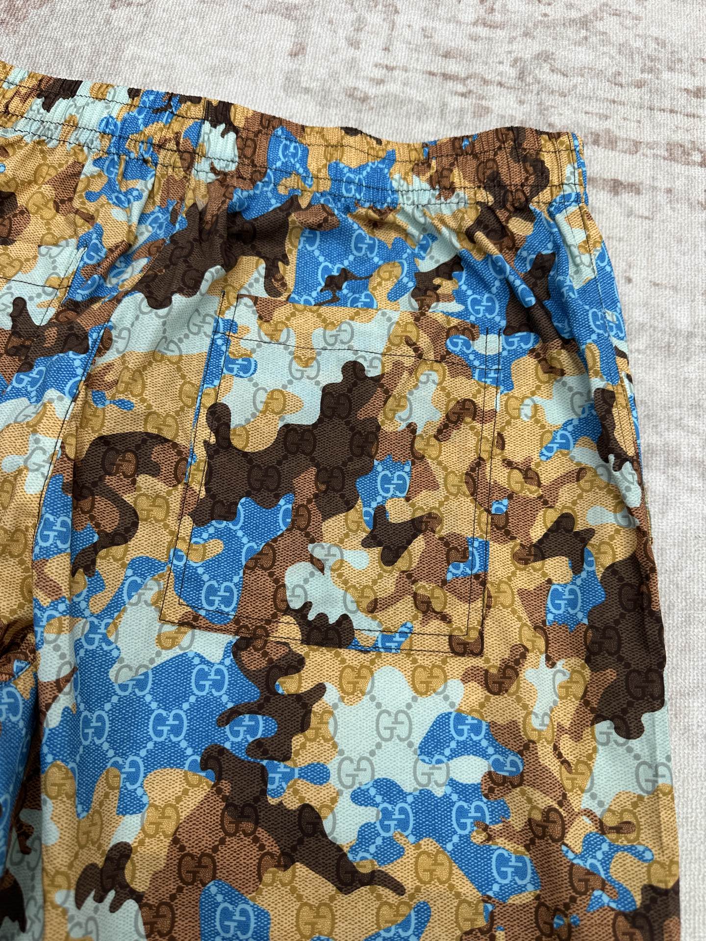 Gucci shorts waistband and side panel with blue, tan, and brown allover print