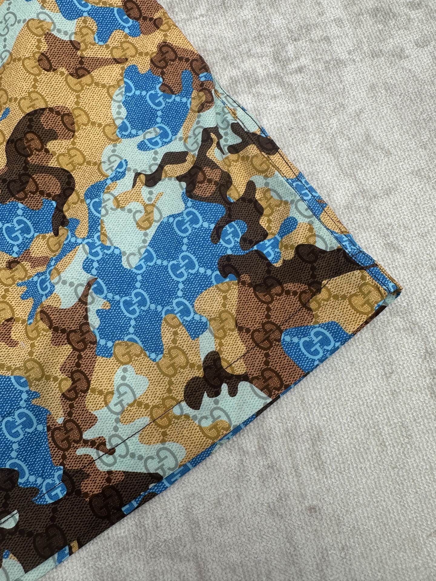 Gucci shorts side view with blue and brown patterned fabric and stitched hem