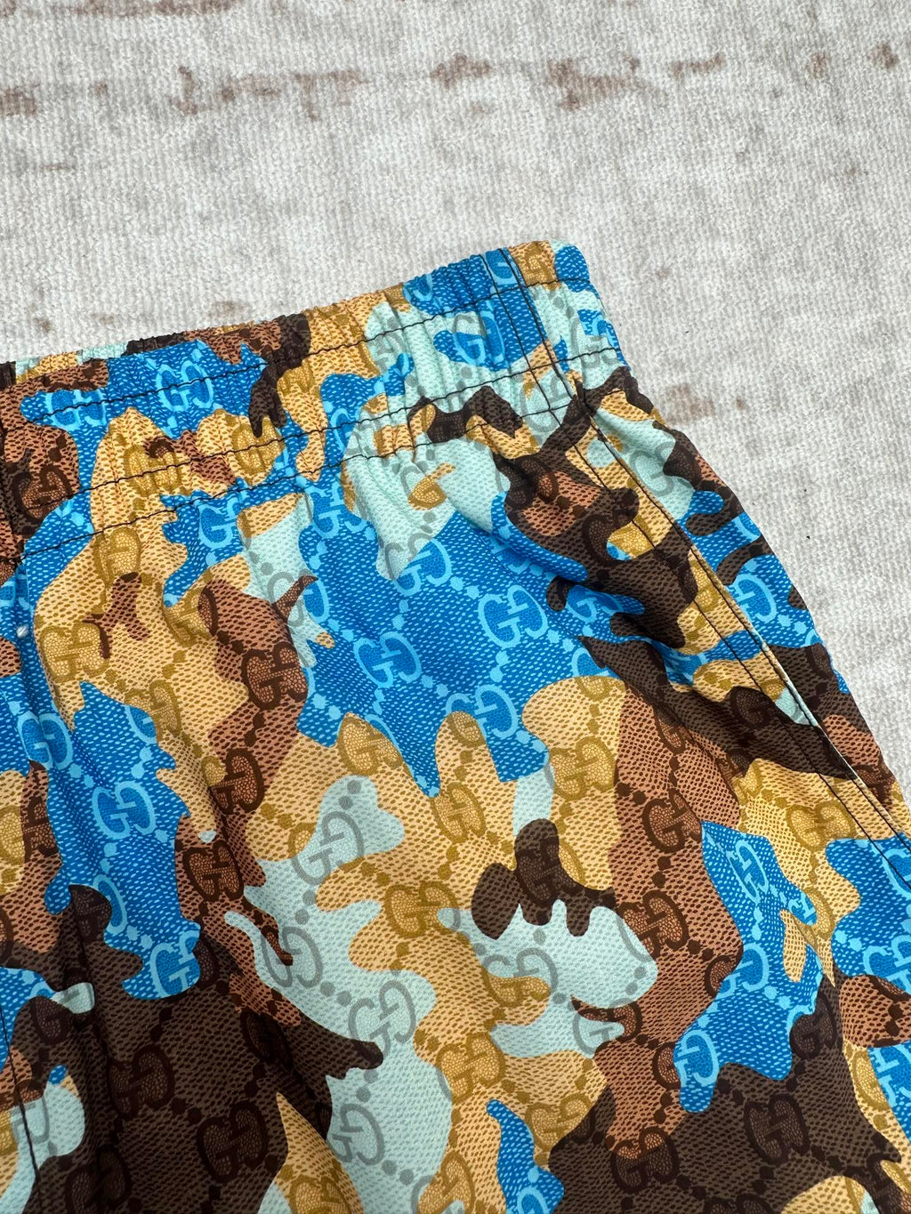 Close-up of Gucci shorts fabric: blue and brown allover camo print pattern