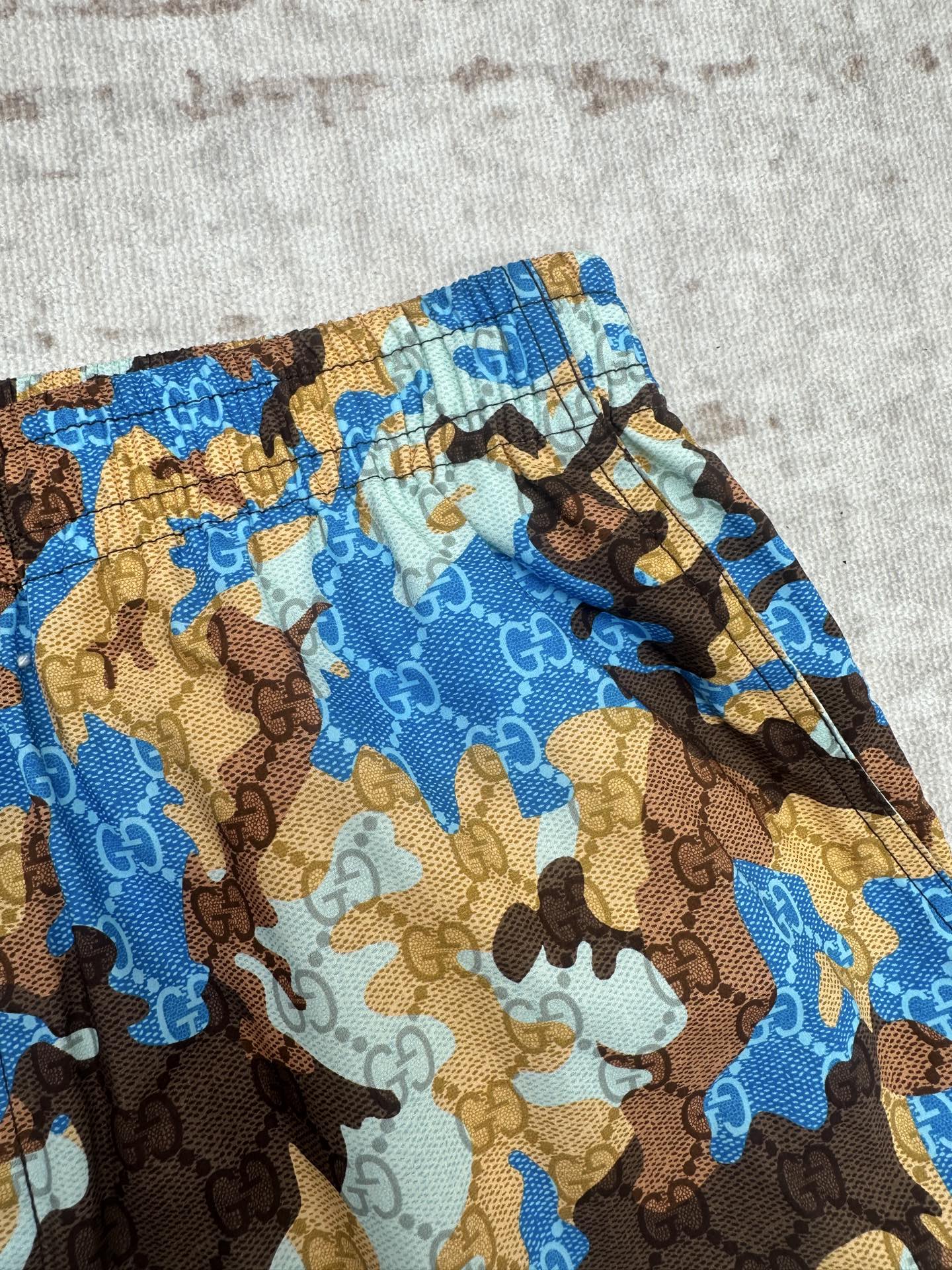Close-up of Gucci shorts fabric: blue and brown allover camo print pattern