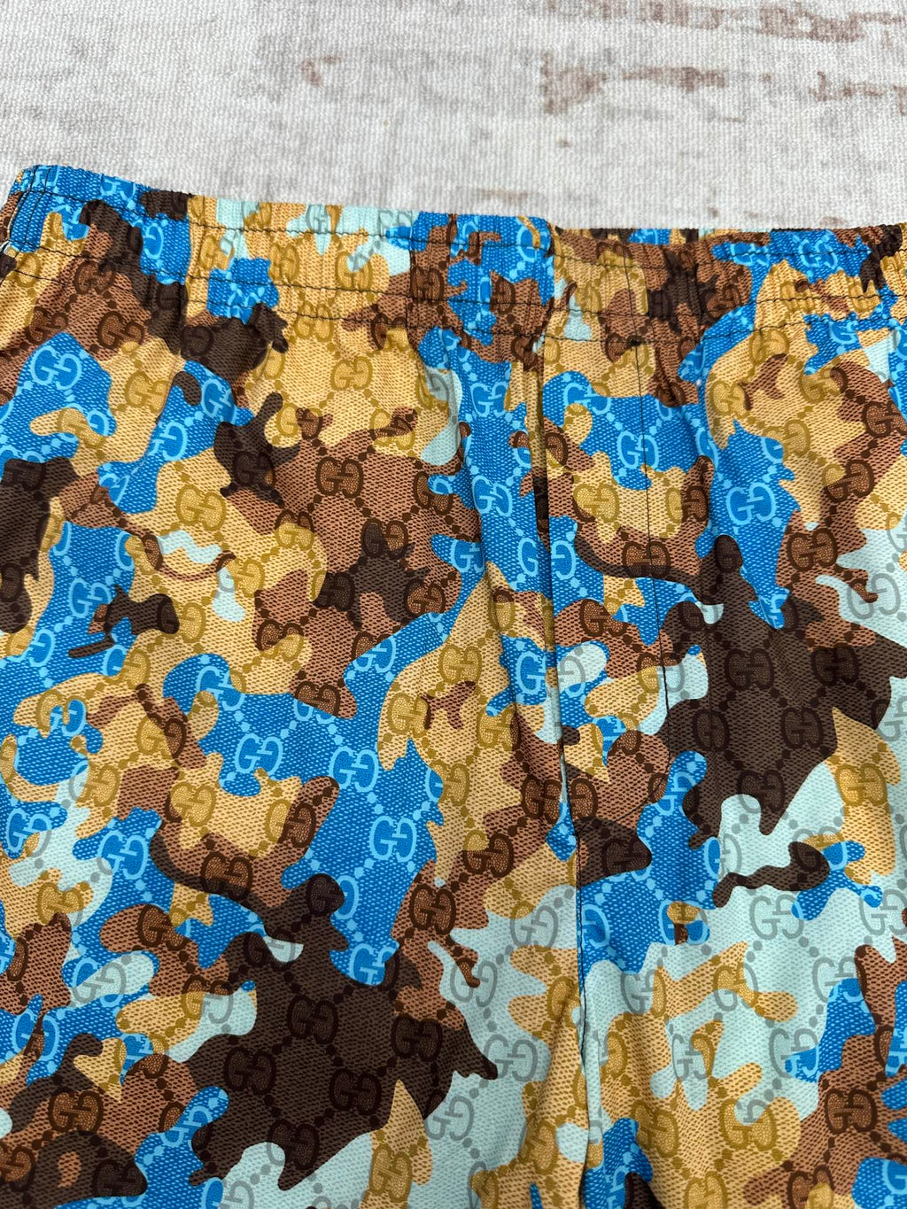 Close-up of Gucci shorts fabric with blue, tan, and brown patterned design