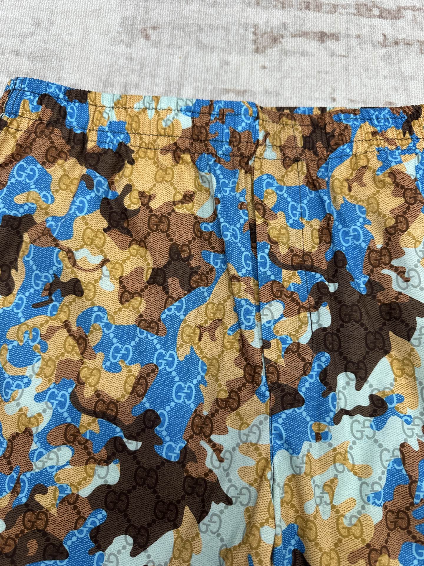 Close-up of Gucci shorts fabric with blue, tan, and brown patterned design