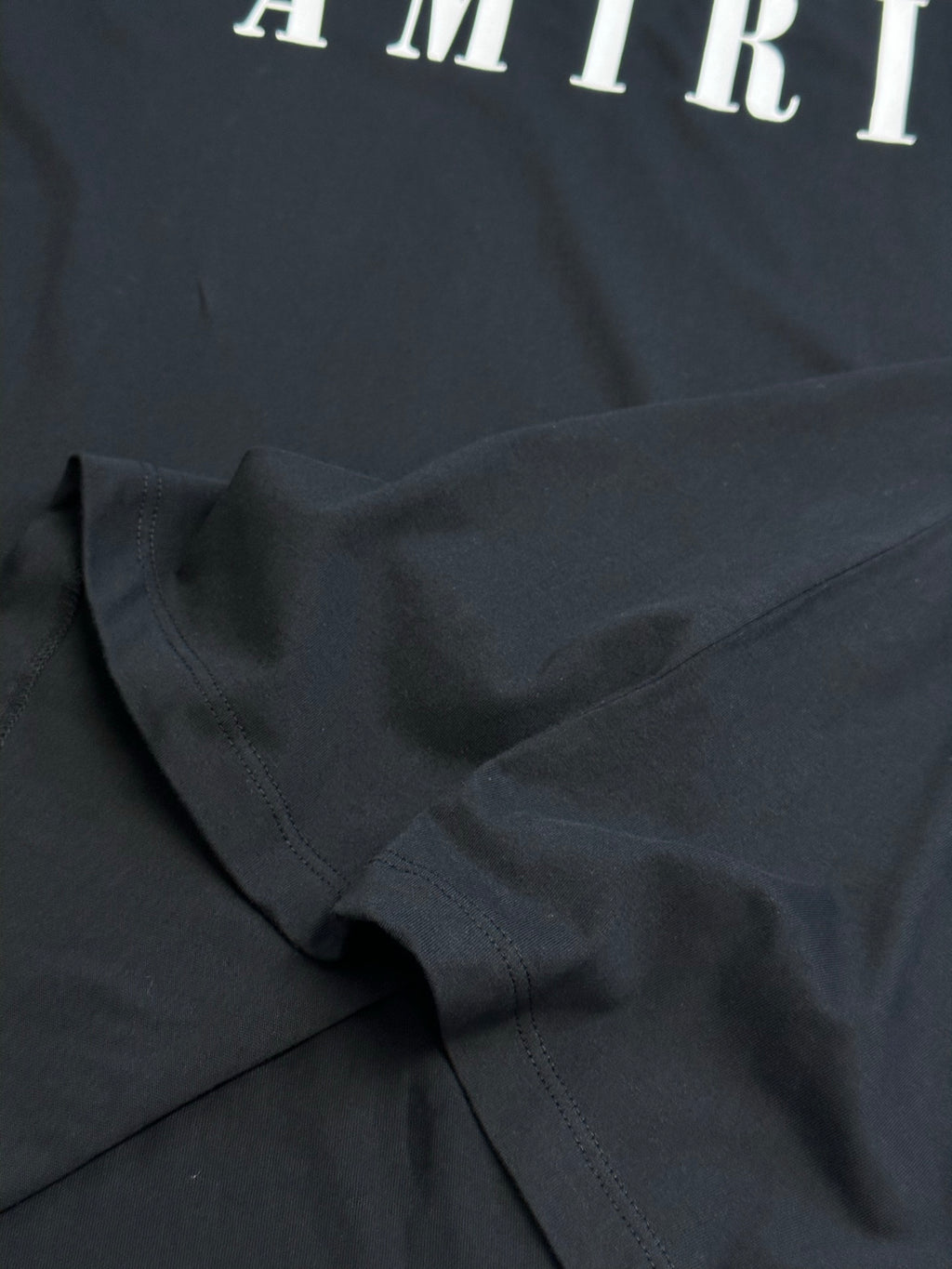 Black Amiri T-shirt fabric close-up with stitched seam