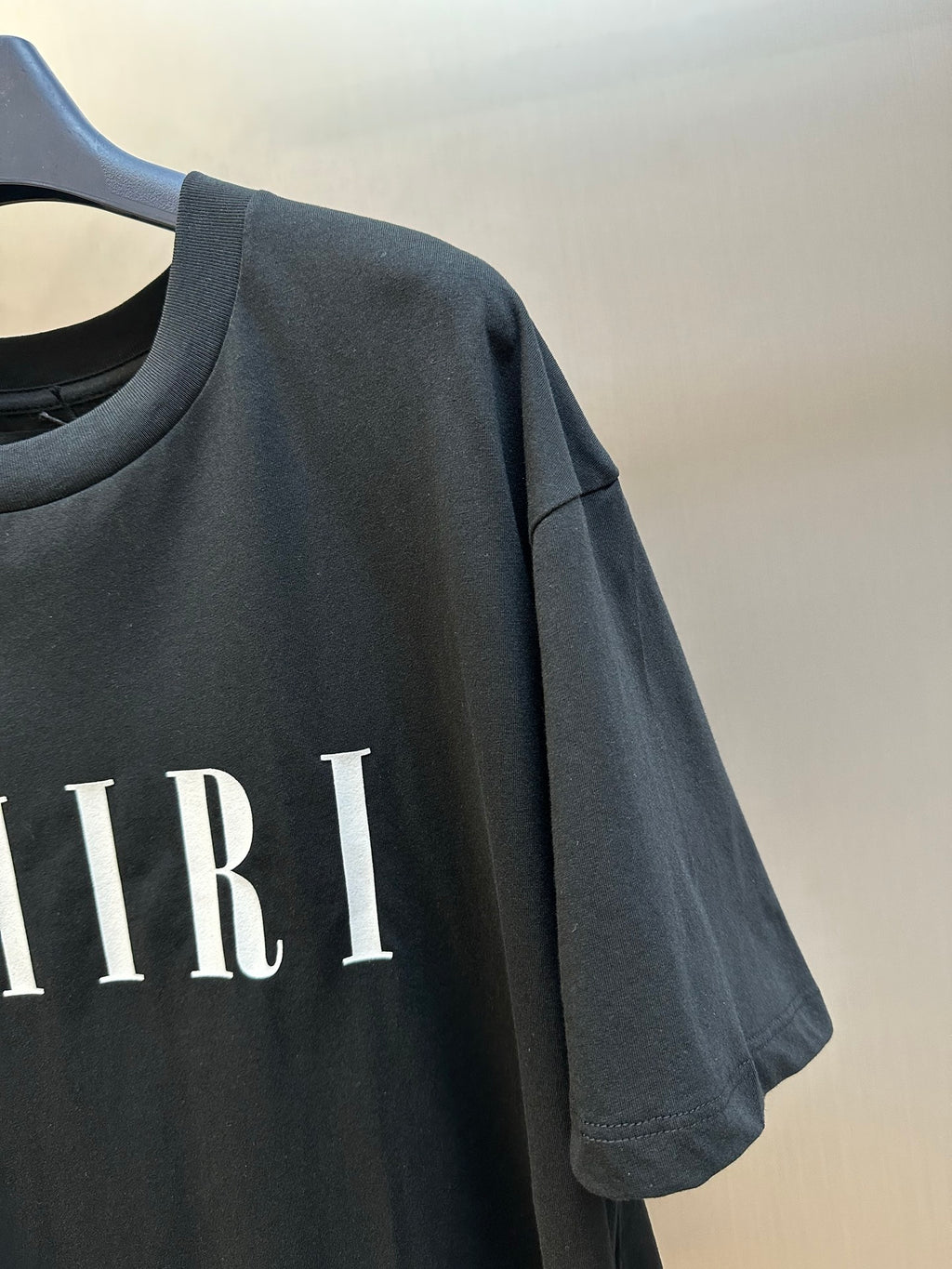 Black Amiri T-shirt sleeve with partial AMIRI lettering print