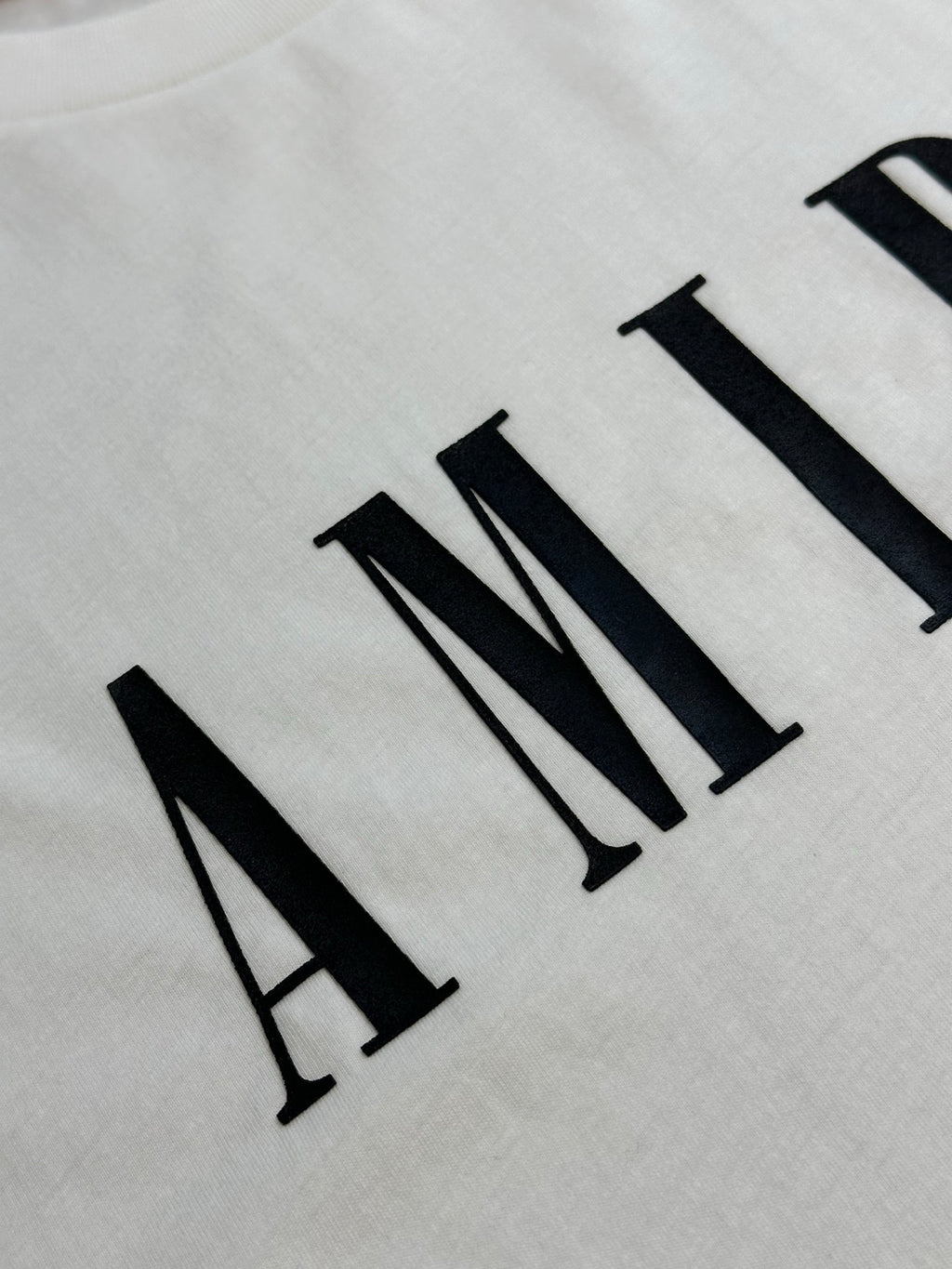 White T-shirt fabric with black AMIRI logo lettering close-up