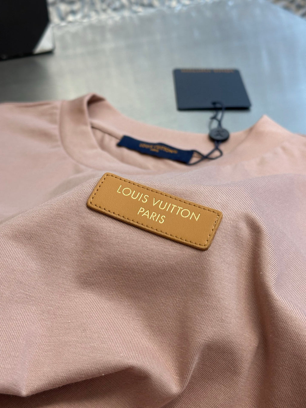 Light pink T-shirt with yellow logo patch and navy inner neck label