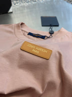 Light pink T-shirt with yellow logo patch and navy inner neck label