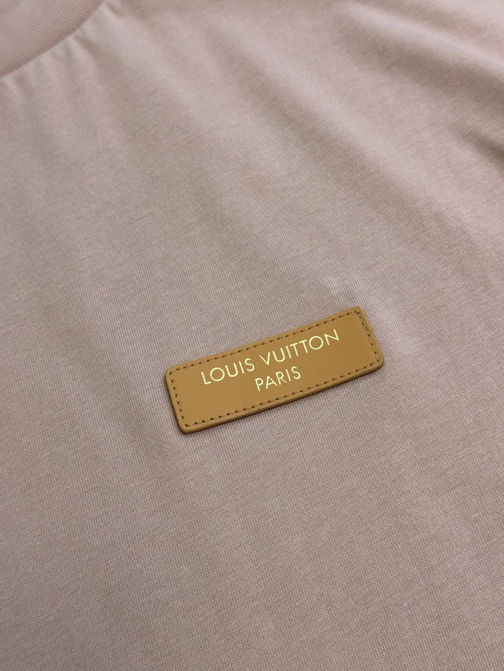 Leather-look logo patch with text on a light pink T-shirt