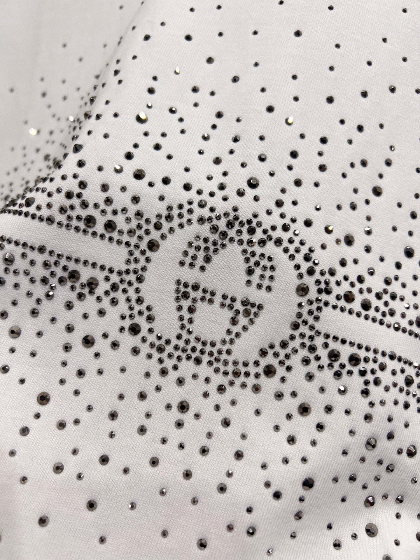 Gucci white T-shirt detail: dense rhinestone speckle fabric with centered logo