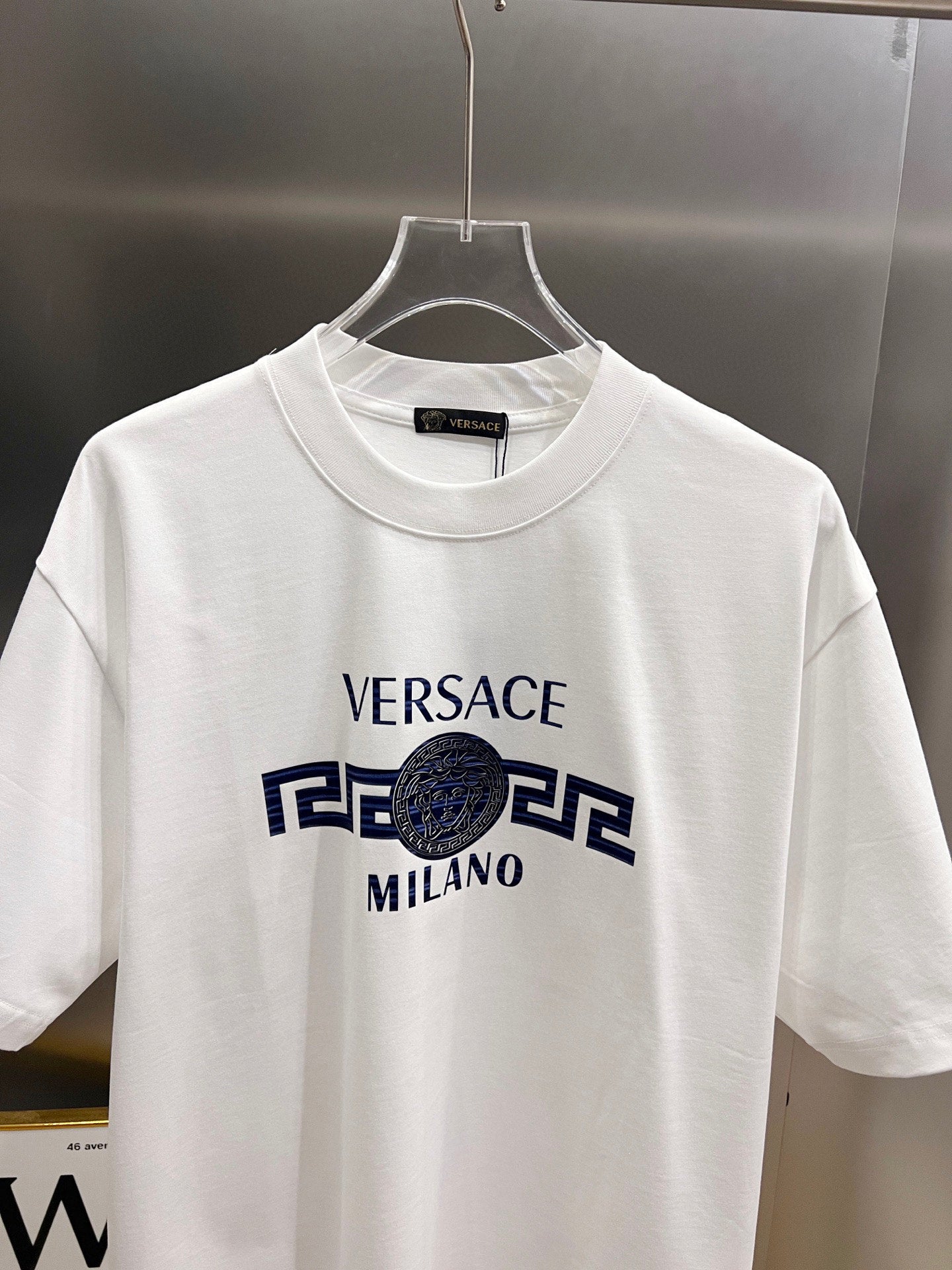 White crewneck short-sleeve T-shirt on hanger with Versace Milano graphic print