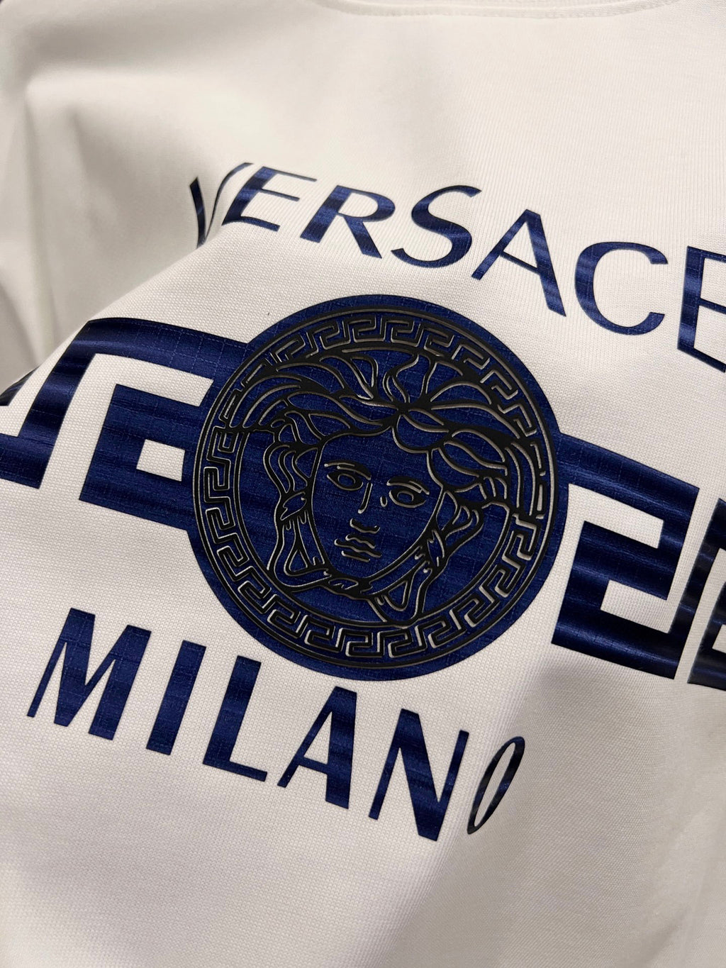 White T-shirt close-up of blue Versace Milano face logo print