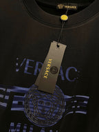 Black T-shirt close-up with blue 'VERSACE' print and round medallion