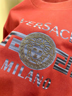 Orange-red Versace T-shirt close-up with Medusa emblem and Milano text