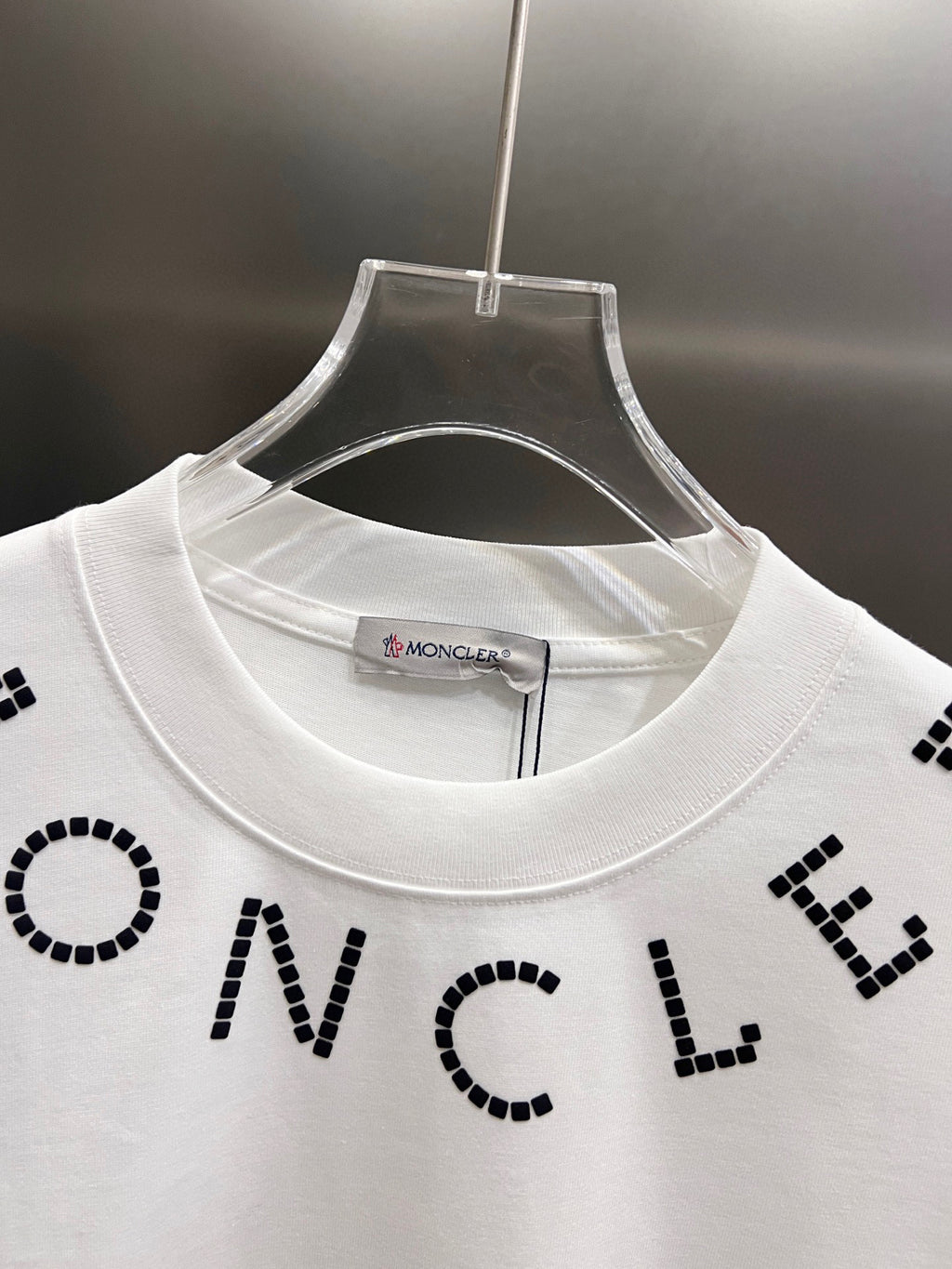 White short-sleeve T-shirt close-up at crew neck with black dotted letter print