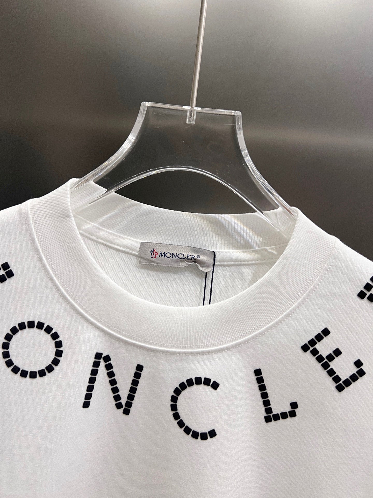 White short-sleeve T-shirt close-up at crew neck with black dotted letter print